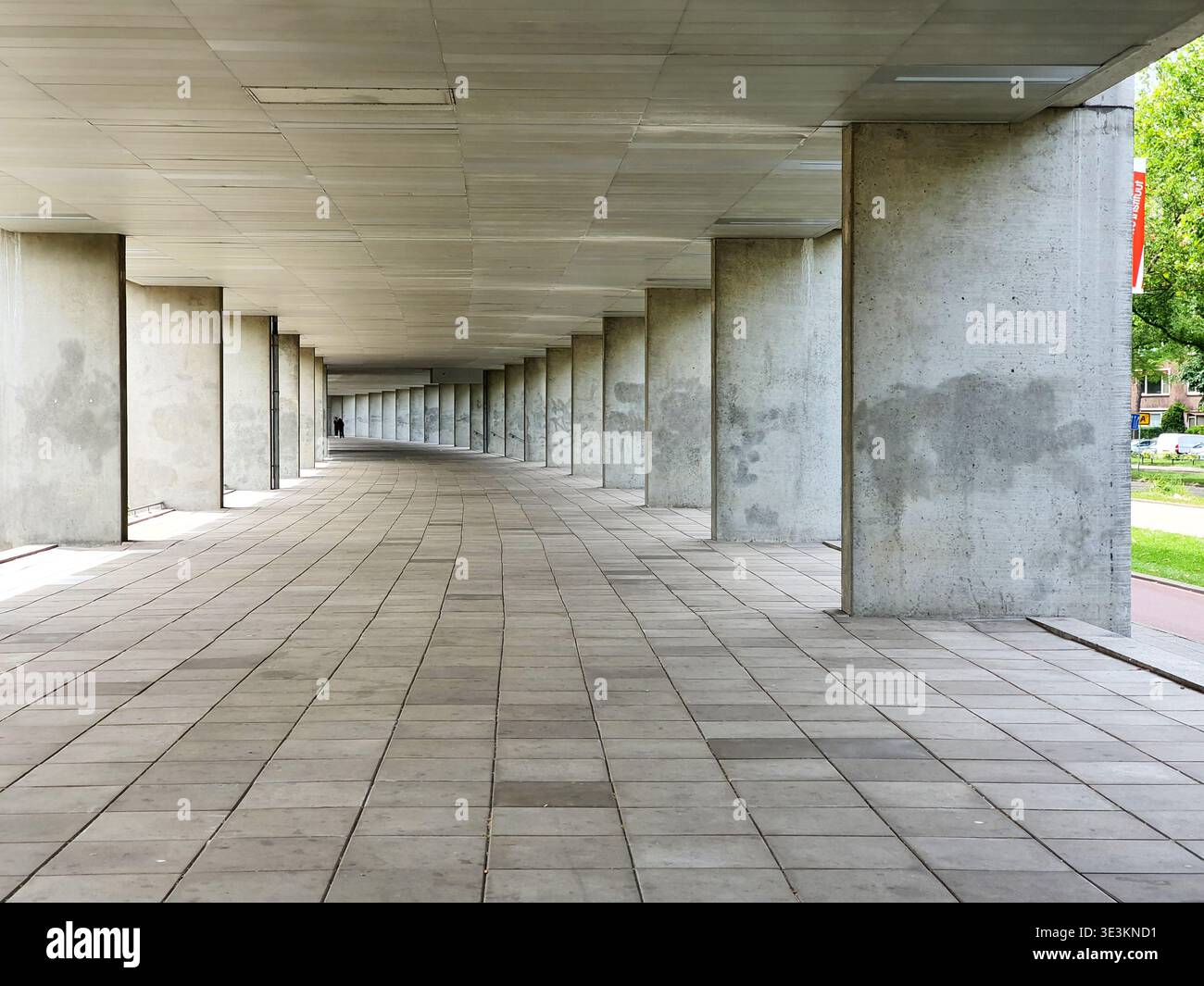 Eine lange, überdachte Säulenhalle im Freien mit massiven Säulen aus Rohbeton, die in die Ferne zurücktreten und eine dramatische lineare Perspektive schaffen Stockfoto
