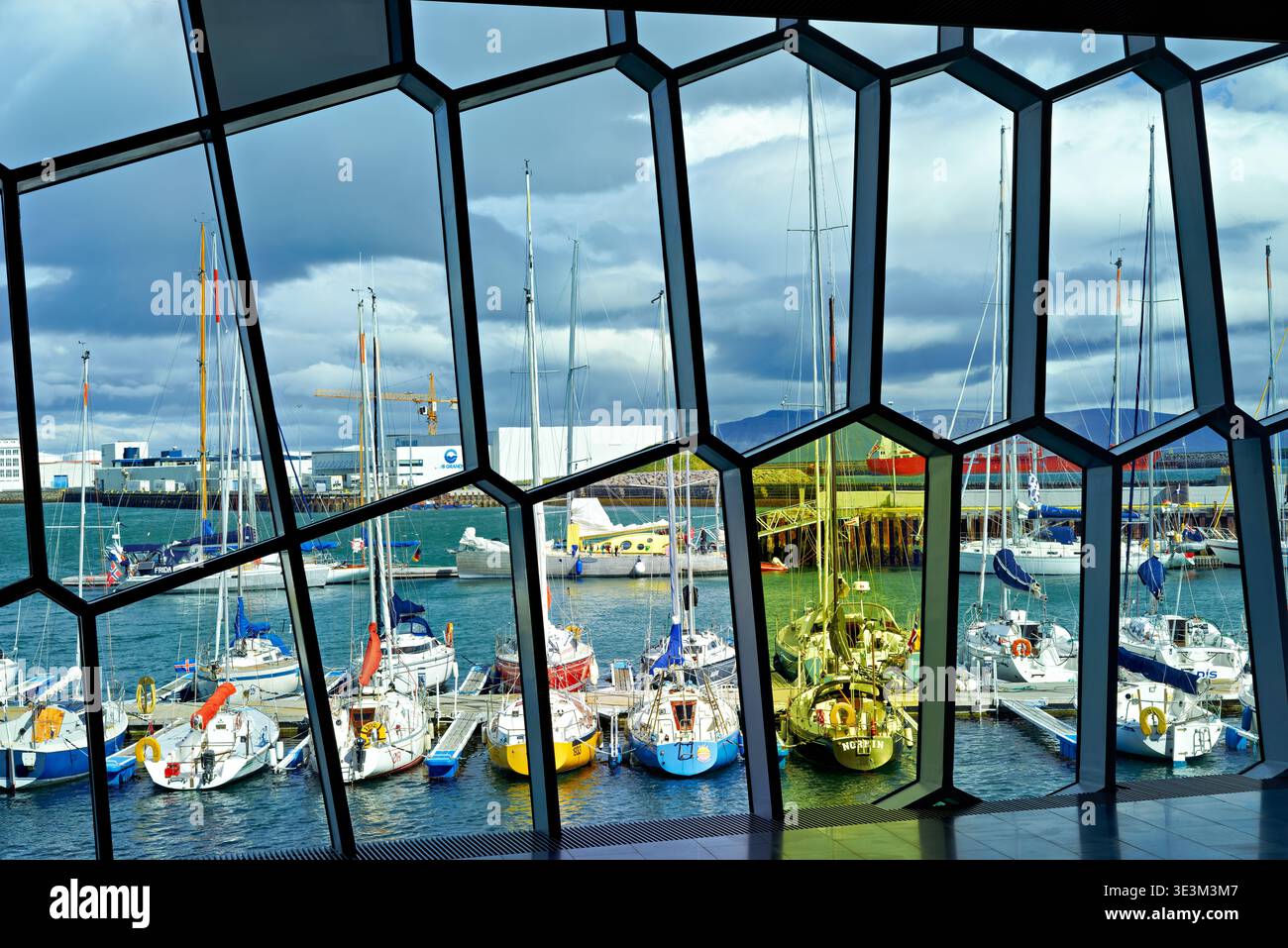 Die Ansicht zeigt Boote, die im Hafen von Harpa Opera House in Reykjavik angedockt sind. Wolken sind am Himmel über der Szene sichtbar. Stockfoto