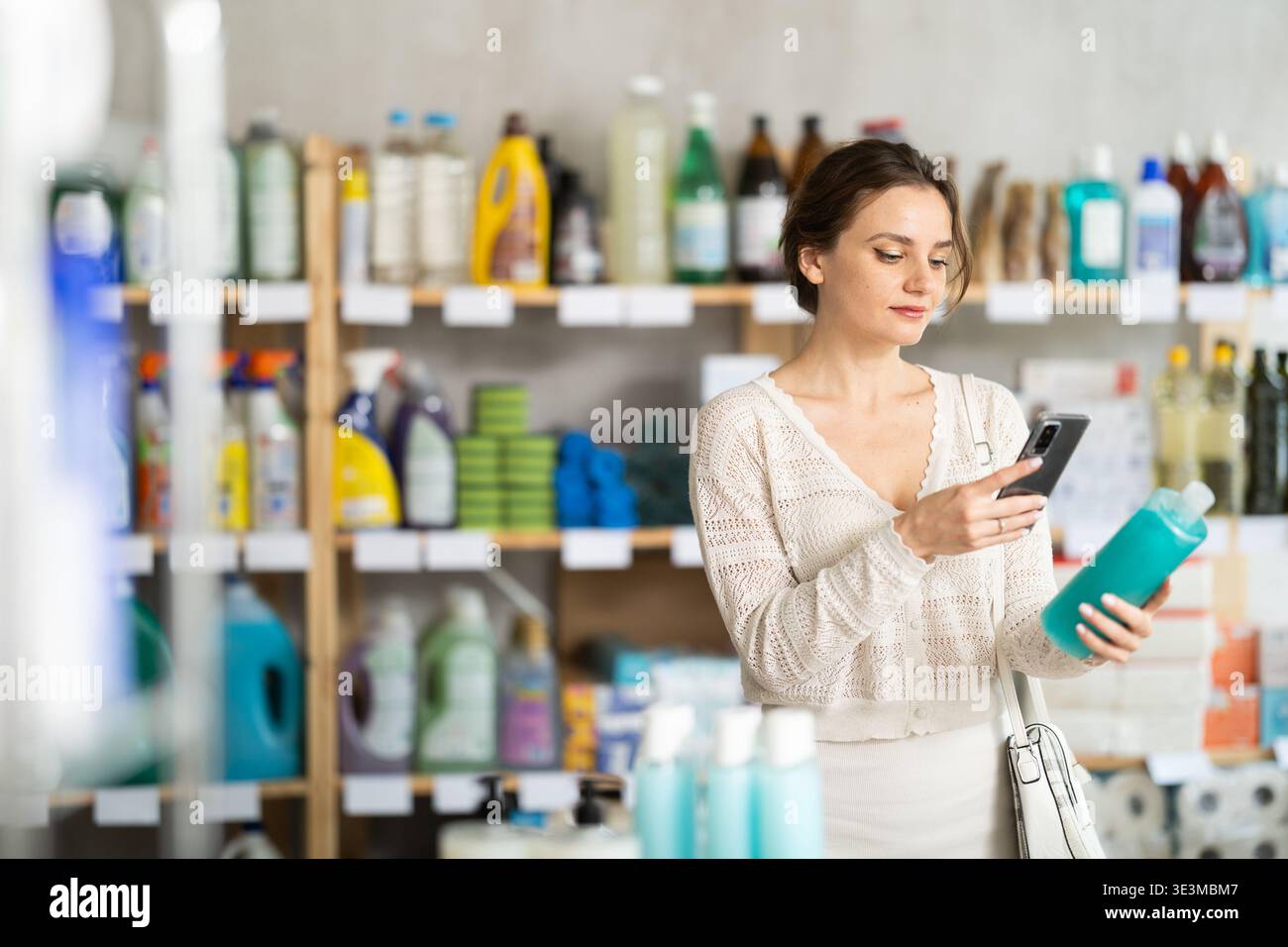 Junge Frau scannt qr-Code nach Shampoo oder Duschgel Stockfoto