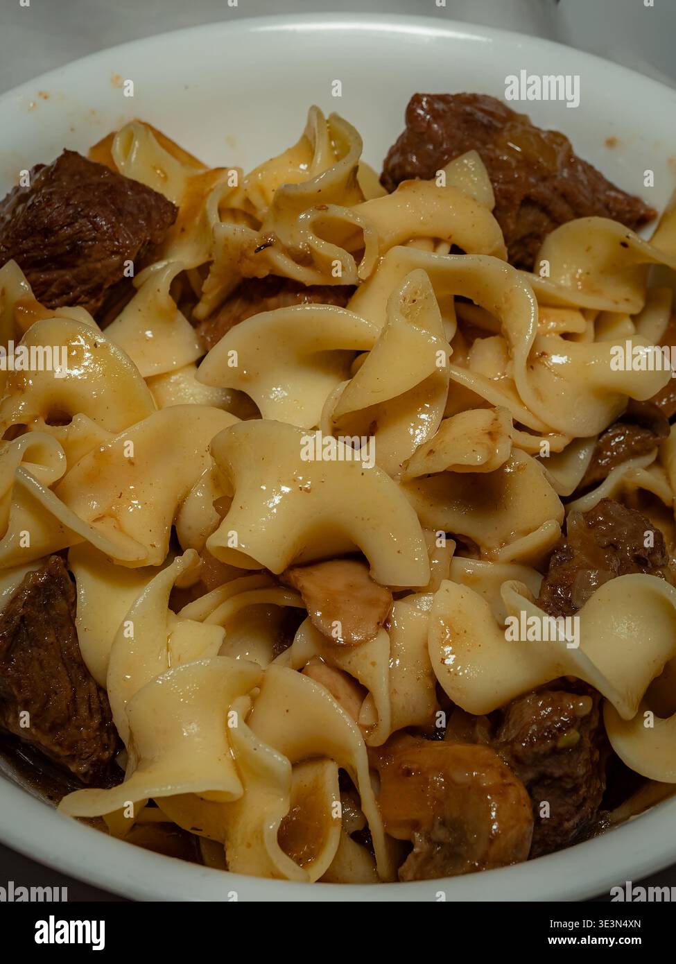 Ein Makroblick von oben nach unten auf eine Schüssel mit Rindfleisch-Stroganoff mit breiten Eiernudeln und Steak-Stücken in einer cremigen Pilzsauce Stockfoto