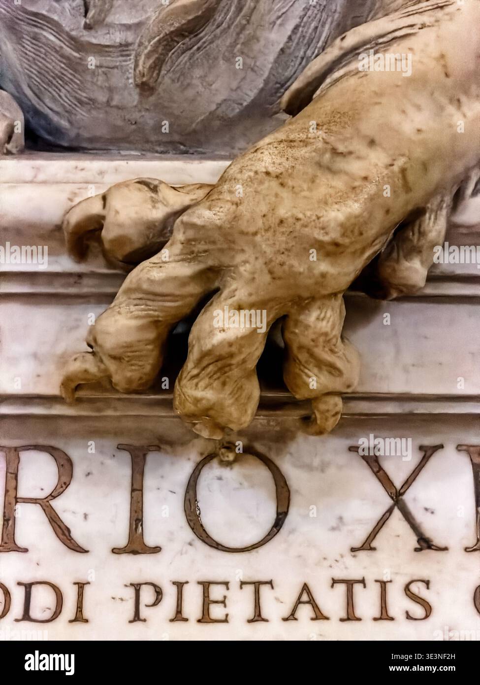 Dekorative Löwenklaue aus Stein überlagert Text auf einem Gedenkgrab in der Petersbasilika im Vatikan. Stockfoto