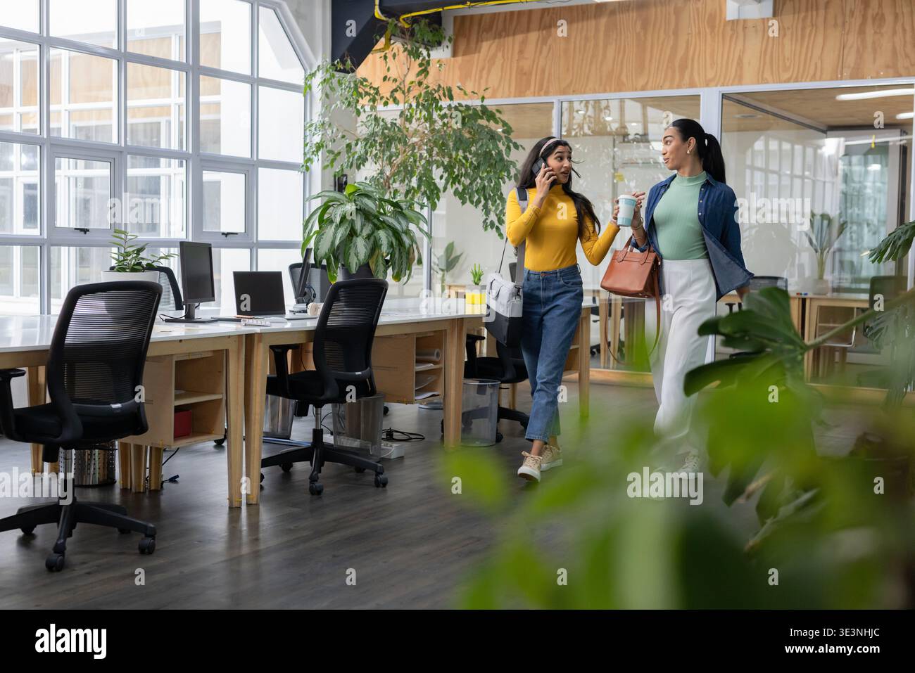 Verschiedene weibliche Kollegen, die mit einer Einkaufstasche im Büro unterwegs sind und Kaffee trinken, Telefon und Kopierraum überprüfen Stockfoto