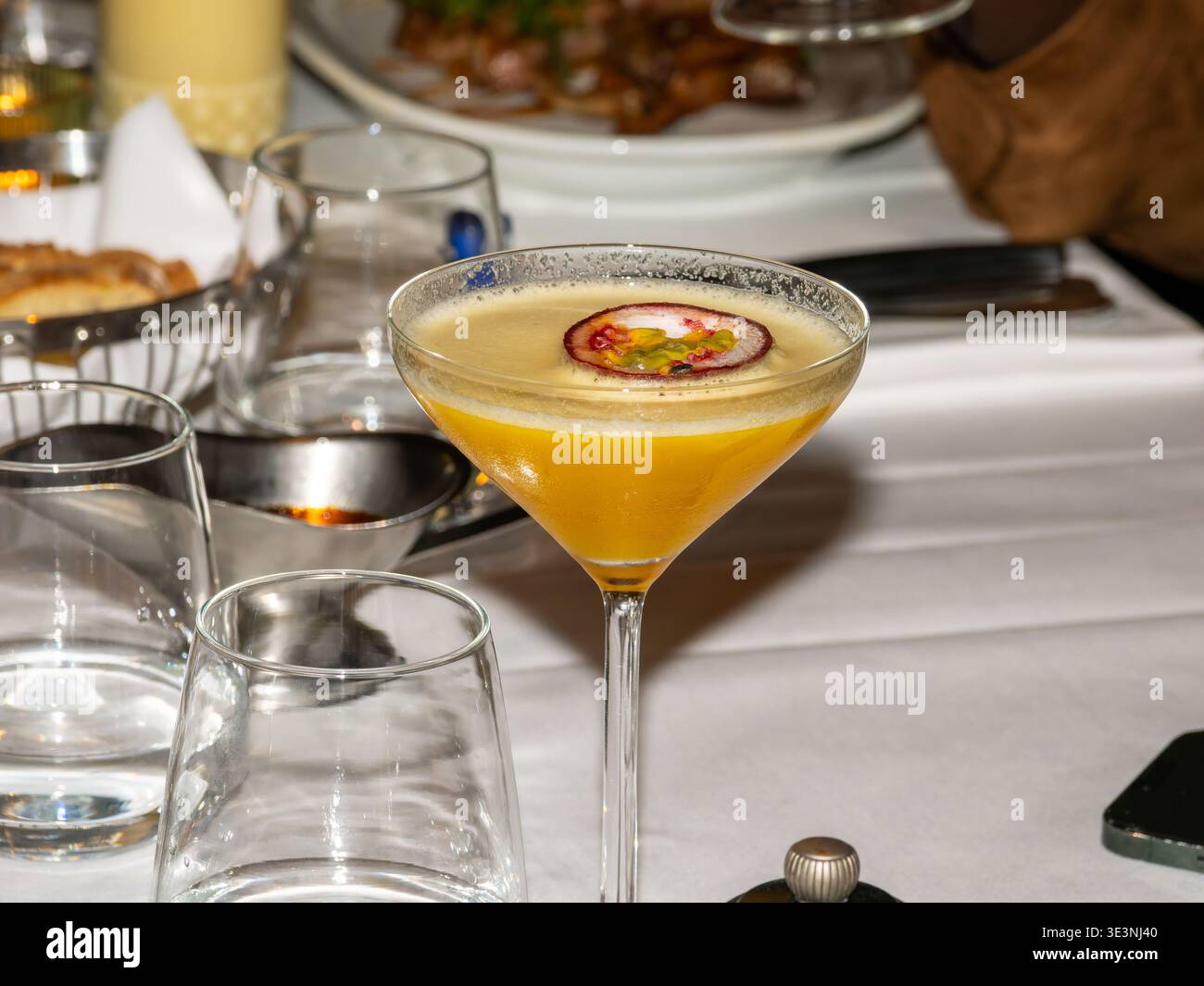 Passionsfrucht-Cocktail, serviert in einem Martini-Glas auf dem Restauranttisch, mit frischen Garnituren und eleganter Präsentation. Stockfoto