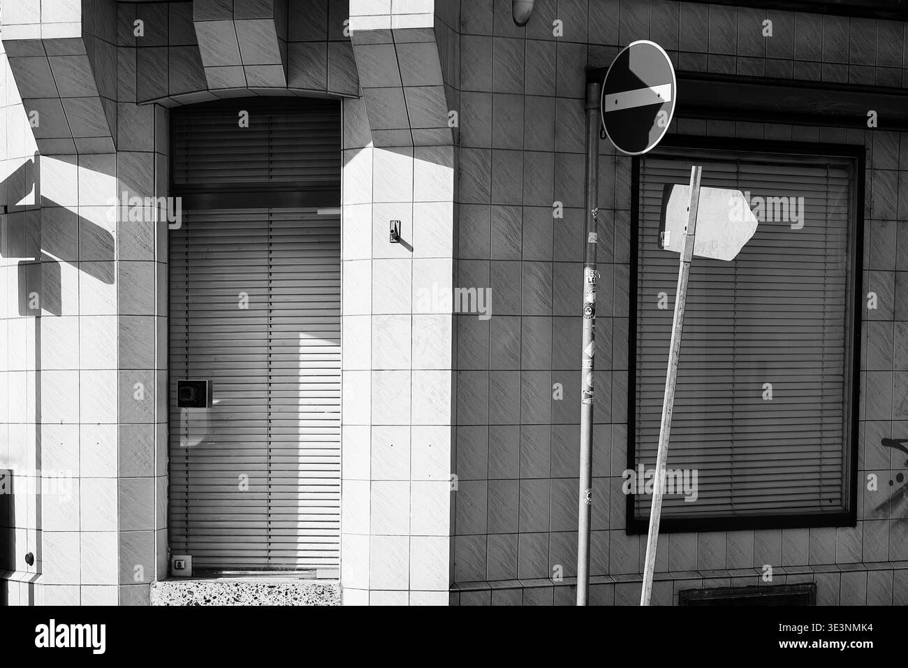 Straßenszene in Schwarz-weiß mit Haus- und Straßenschildern in Licht und Schatten Stockfoto