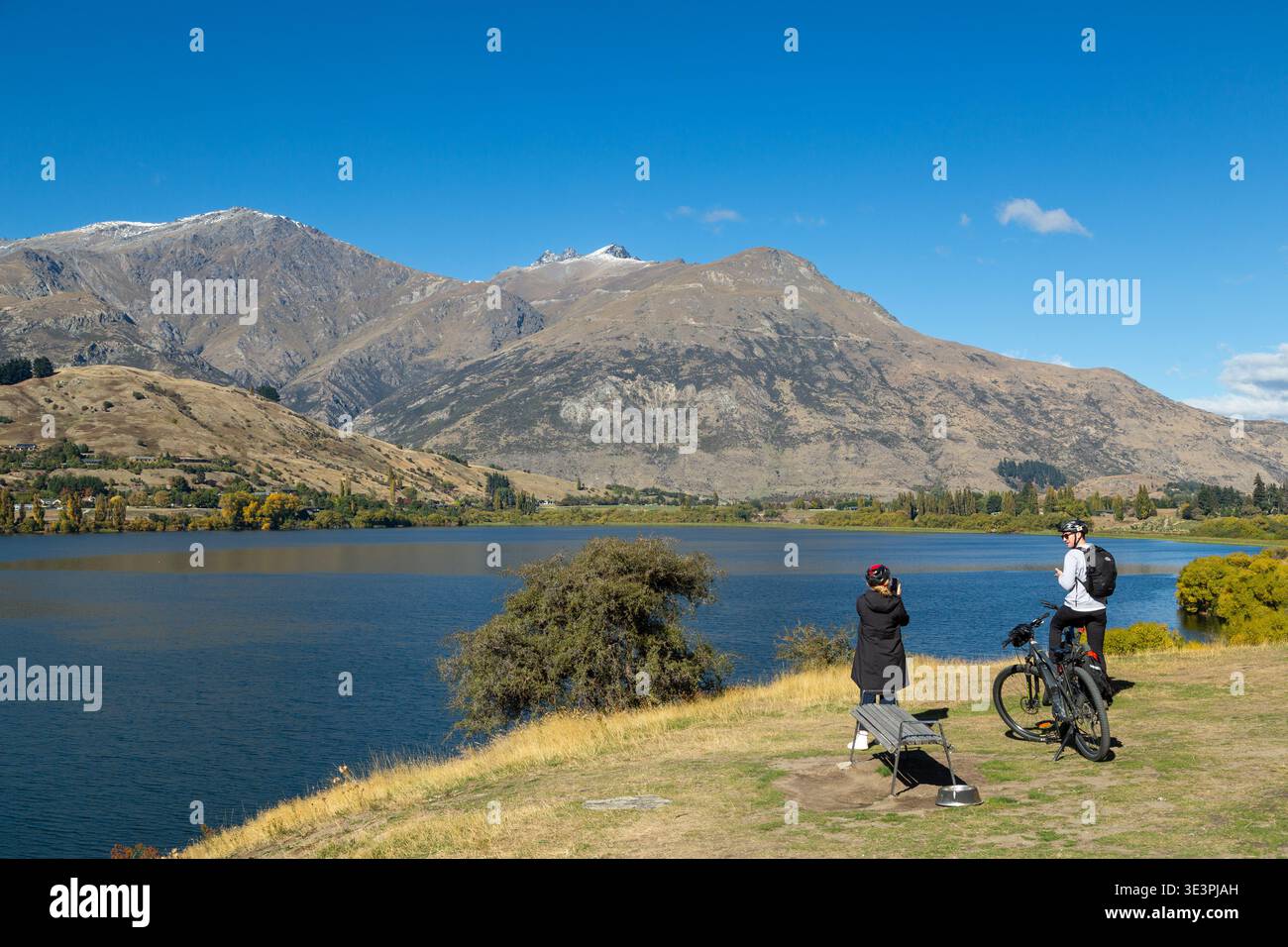Touristen, die an einem hellen und sonnigen Apriltag Fotos von Lake Hayes und The Remarkables machen, Central Otago, Neuseeland Stockfoto