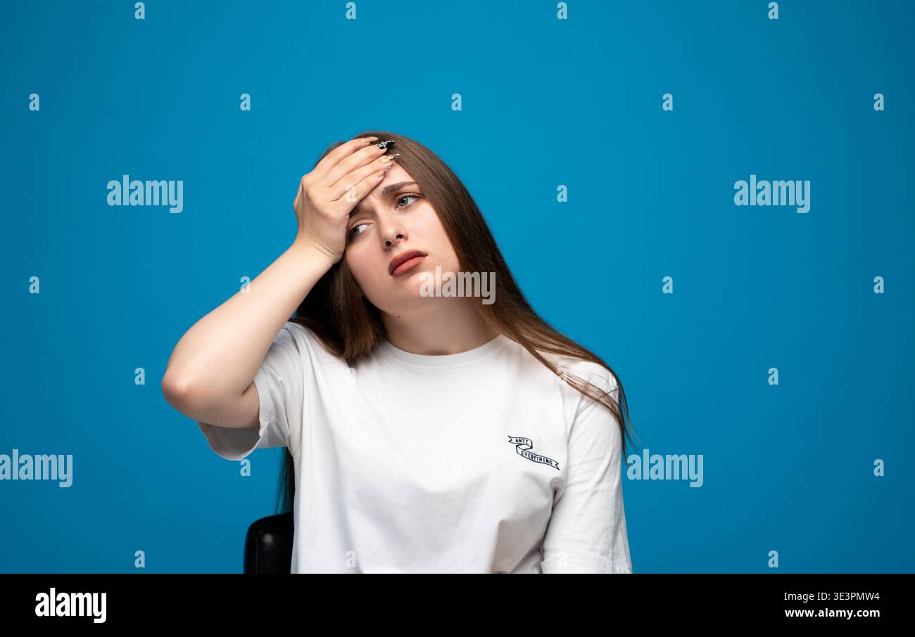 Junge Frau, die an Kopfschmerzen oder Migräne leidet, Schmerzen, Stress oder Fieber spürt und ihre Stirn berührt Stockfoto