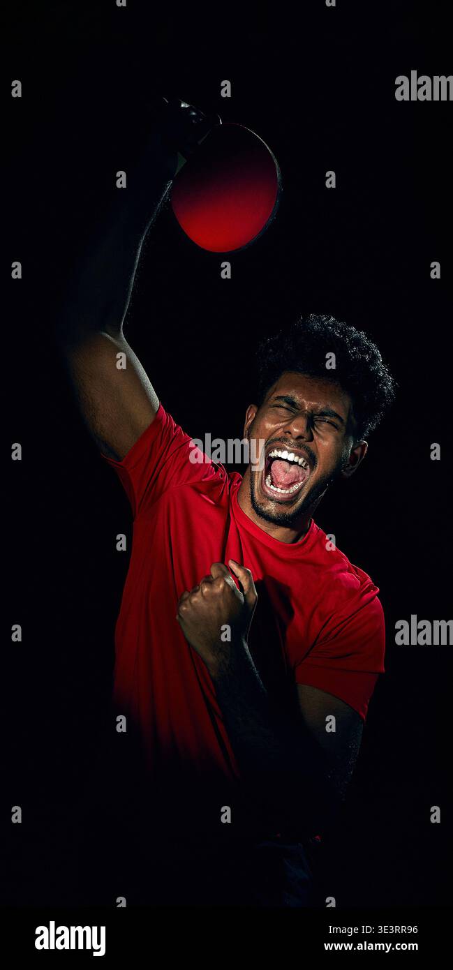 Elite-Tischtennisspieler trainiert Reaktionsgeschwindigkeit mit schnellem Ball im dunklen Studio. Stockfoto