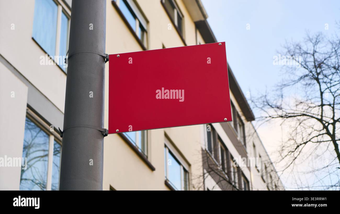 Mockup-Vorlage für Werbeflächen mit einem roten Schild an einem Stab in einer städtischen Umgebung bietet das leere Schild leeren Platz für eine Nachricht oder Werbung Stockfoto