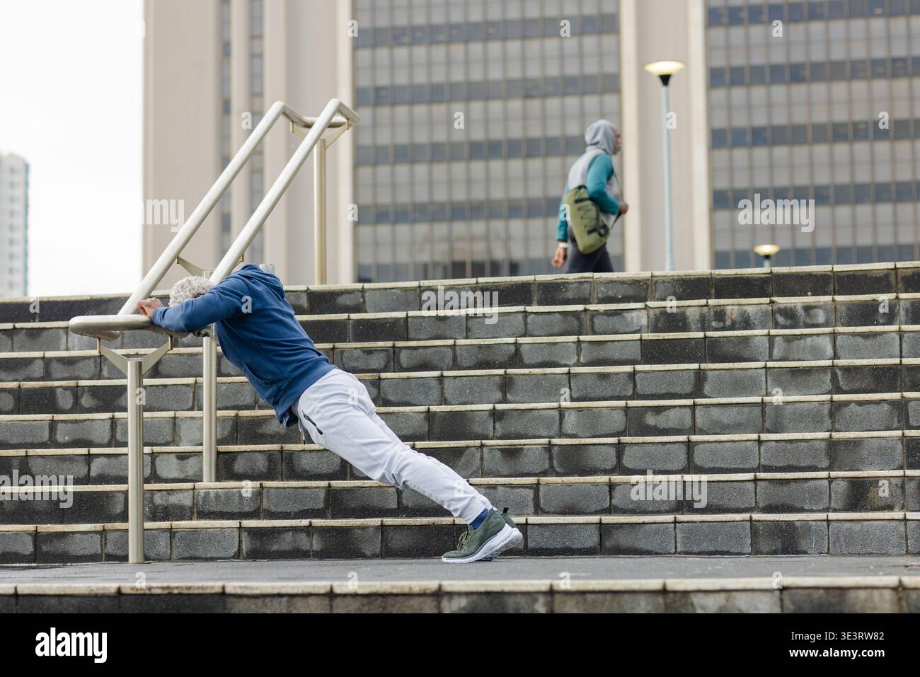 Ranghoher afroamerikanischer Mann, der geneigte Liegestütze am Metallgeländer an der plaza Treppen macht Stockfoto