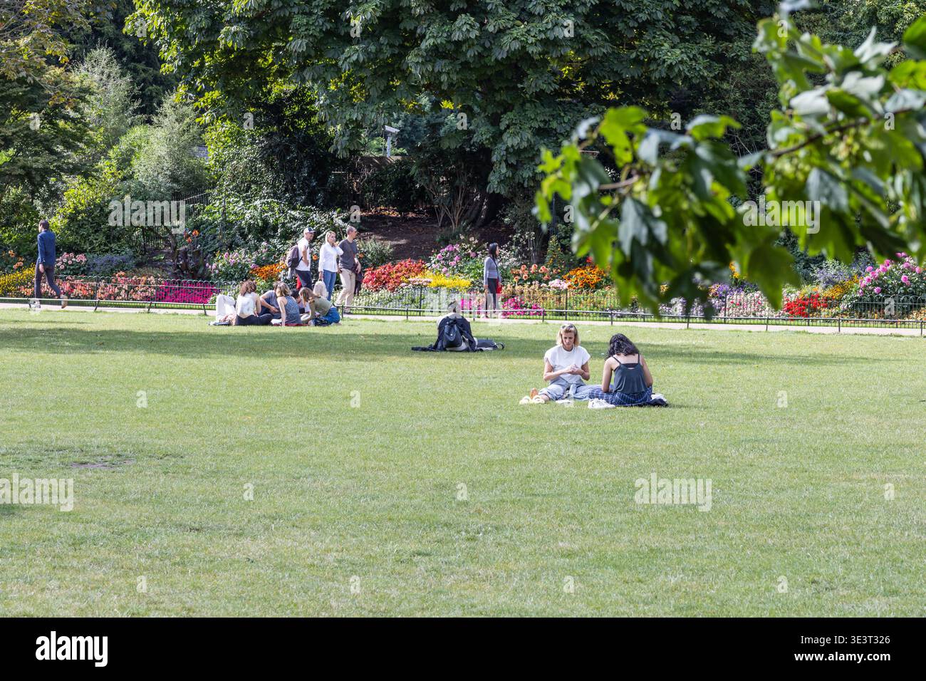 Menschen, die sich auf grünem Gras in einem öffentlichen Park entspannen. London, UK, 23. Juli 2023 Stockfoto