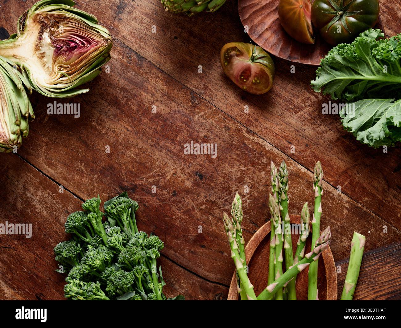 Verschiedene gesunde Gemüsesorten liegen auf einem rustikalen Holztisch bereit für die Zubereitung der Mahlzeiten. Die Farben und Formen heben die Auswahl für eine vegane Mahlzeit hervor. Dies Stockfoto