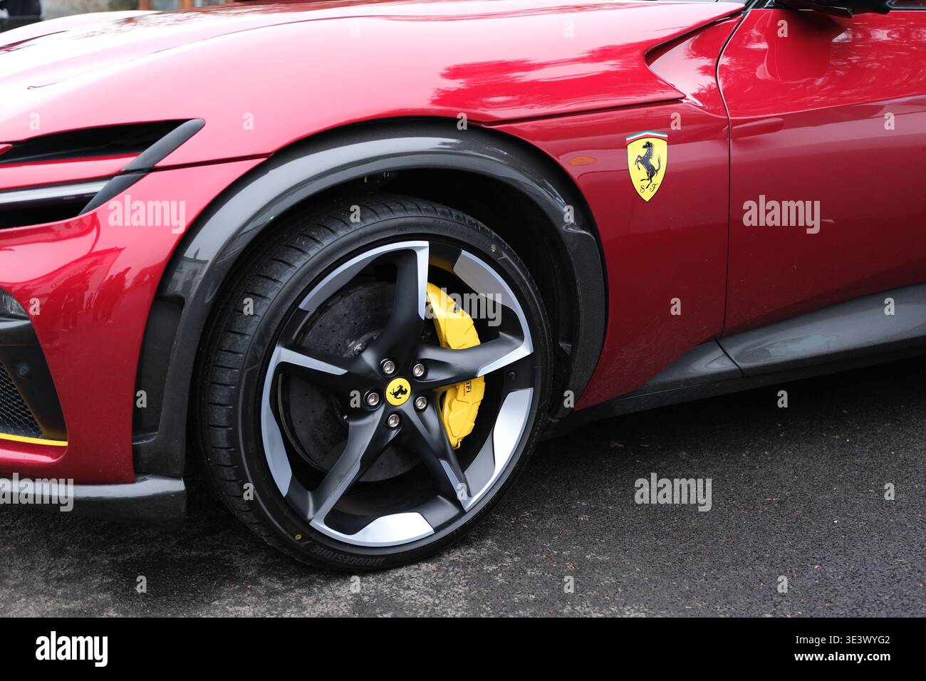 Nahaufnahme des roten Ferrari Purosangue FUV-Laufrads und -Emblems, das das luxuriöse Performance-Design, gelbe Bremssättel und das Markenzeichen eines stolzenden Pferdes hervorheben. Stockfoto
