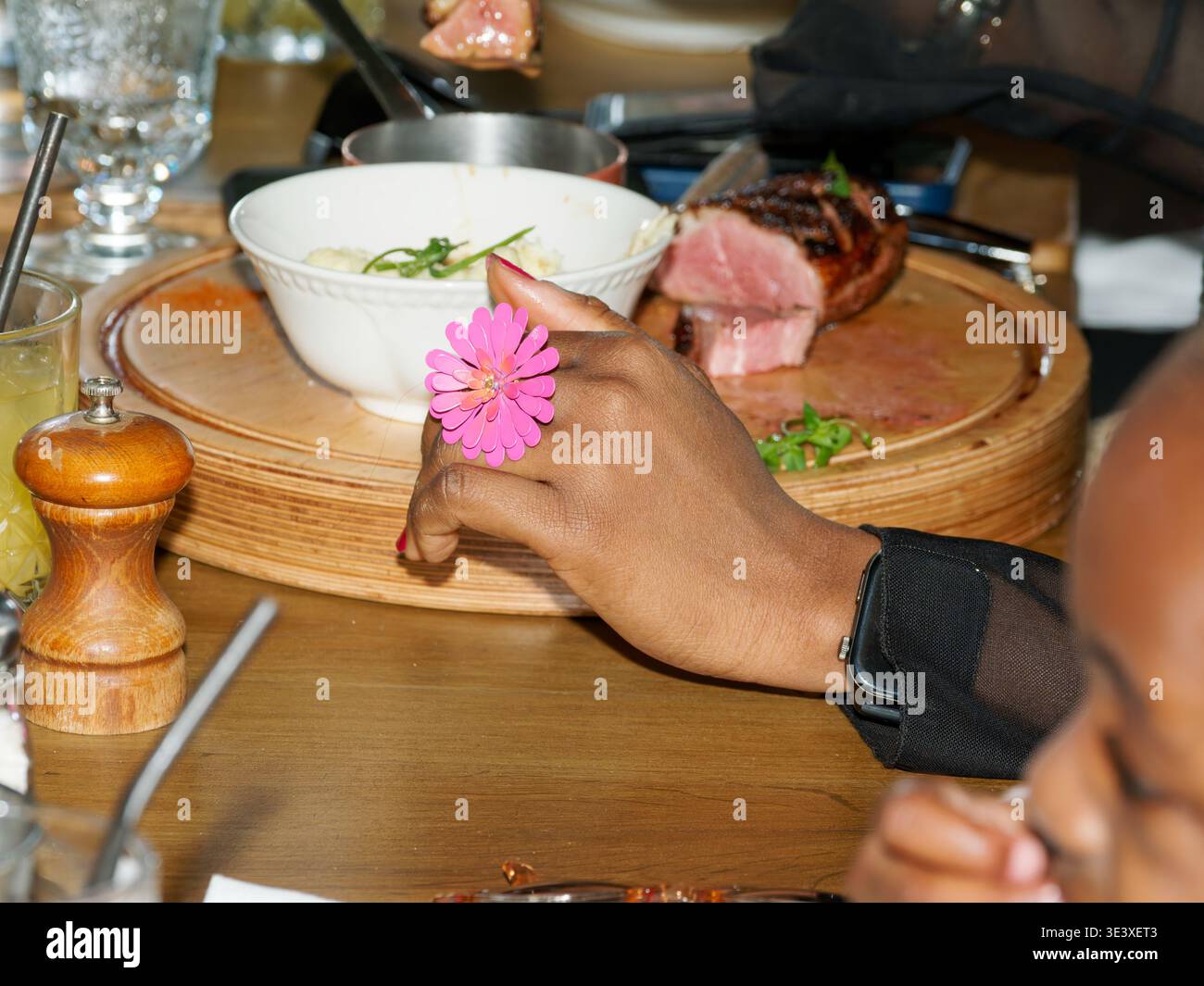 Nahaufnahme einer Person am Restauranttisch mit Essen und Teller, die zwanglose Essensmomente und gesellige Lifestyle-Szene mit gemeinsamer Mahlzeit zeigt. Stockfoto