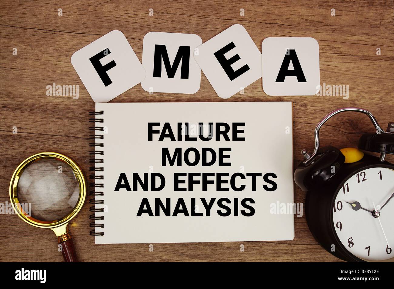Text der FMEA-Fehlermodus- und Effektanalyse auf Notizblock mit Lupe und Wecker auf hölzernem Hintergrund Stockfoto
