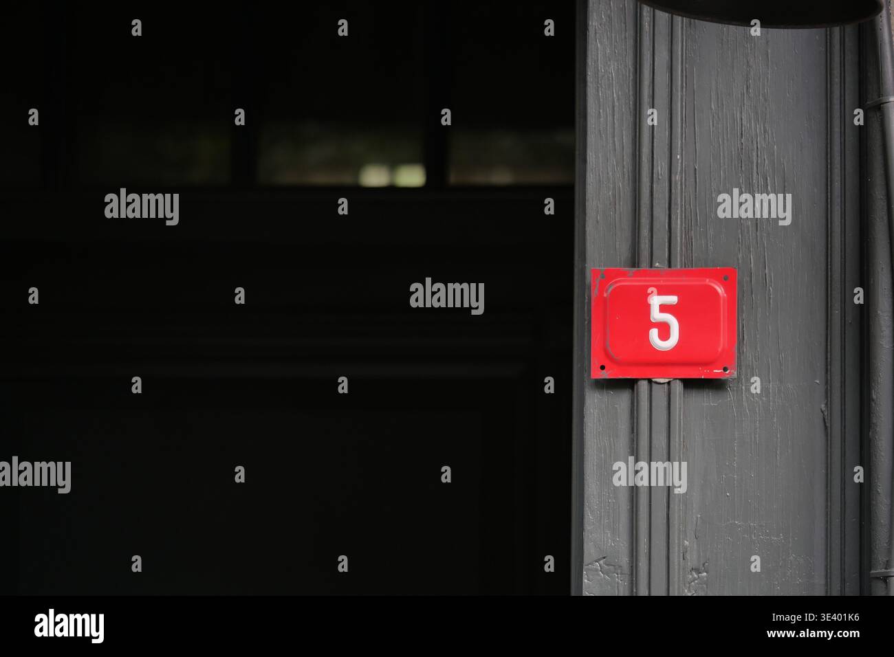 Nummer 5 steht an einer Tür in einem dunklen Gebäude Stockfoto