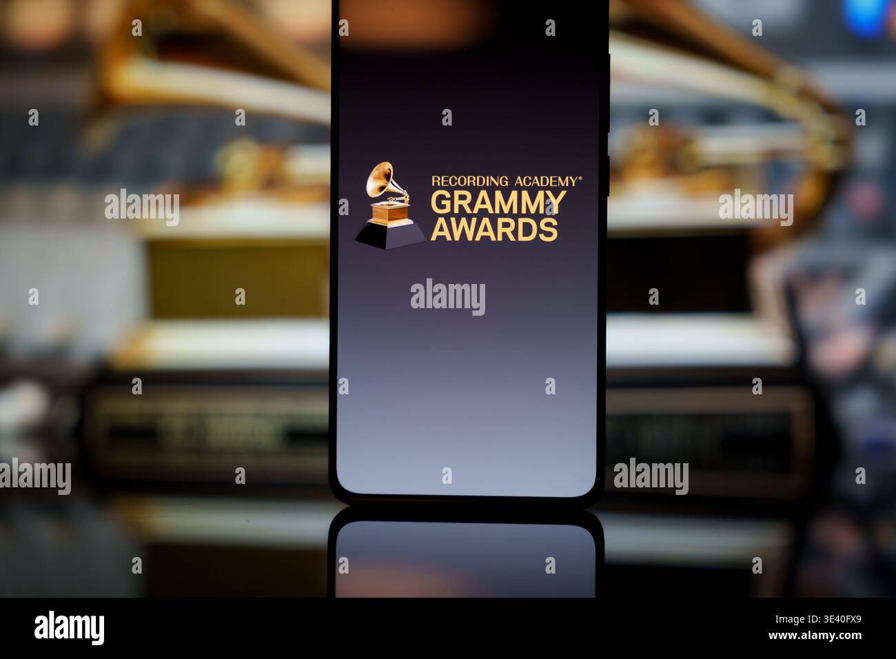 Grammy Awards-Logo auf einem Smartphone-Bildschirm mit verschwommenen goldenen Grammophon-Trophäen im Hintergrund, Auszeichnungen der Musikindustrie und digitaler Streami Stockfoto
