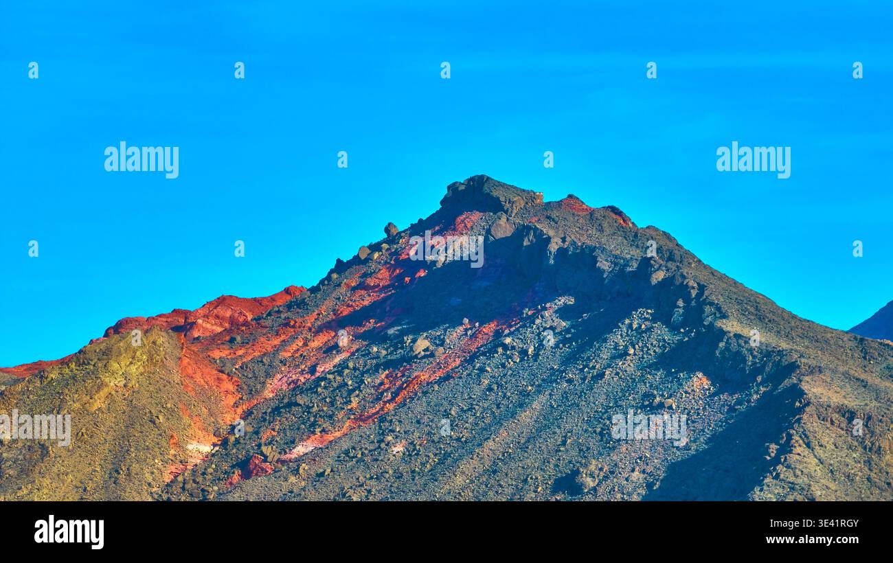 Farbenfroher Mountain Peak mit zerklüfteten Texturen und blauem Himmel in Nevada Stockfoto