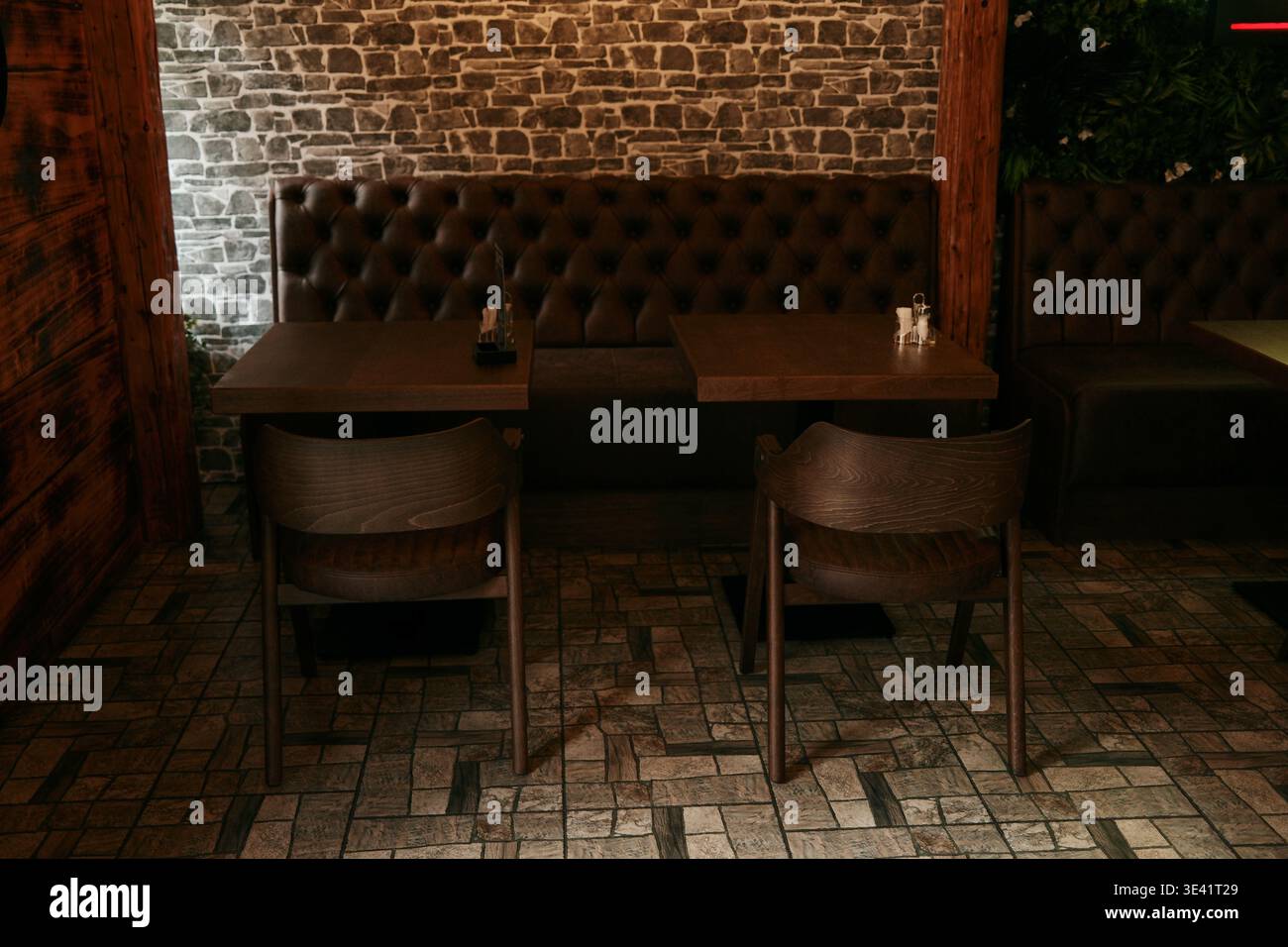 Gemütliches Restaurant mit Holztischen und Ledersofa an der Backsteinwand. Konzept der Gastfreundschaft, des Komforts und der stilvollen Atmosphäre des Restaurants. Stockfoto