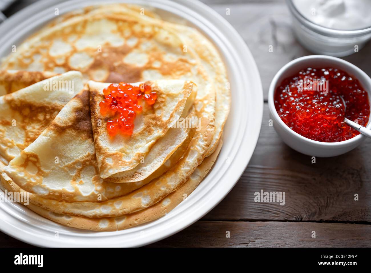 Hausgemachte dünne Crepes mit rotem Kaviar aus nächster Nähe, detailliert. Herzhafte Pfannkuchen mit Lachsfischkaviar. Maslenitsa Pfannkuchenwoche traditionelles Frühstück Stockfoto