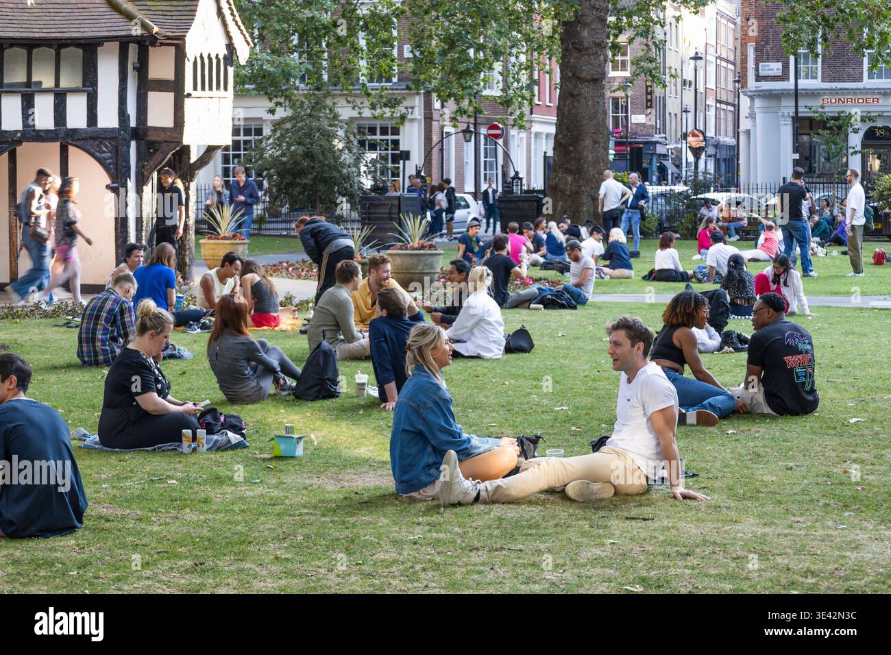 Menschen, die sich auf dem Gras in einem Stadtpark entspannen. London, UK, 23. Juli 2023 Stockfoto