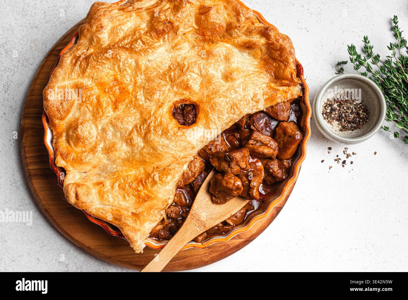 Rindersteakkuchen mit Blätterteig, Thymian und Gewürzen auf weißem Hintergrund, Blick von oben. Hausgemachtes Fleisch-Ale-Pie saisonales Rezept. Stockfoto