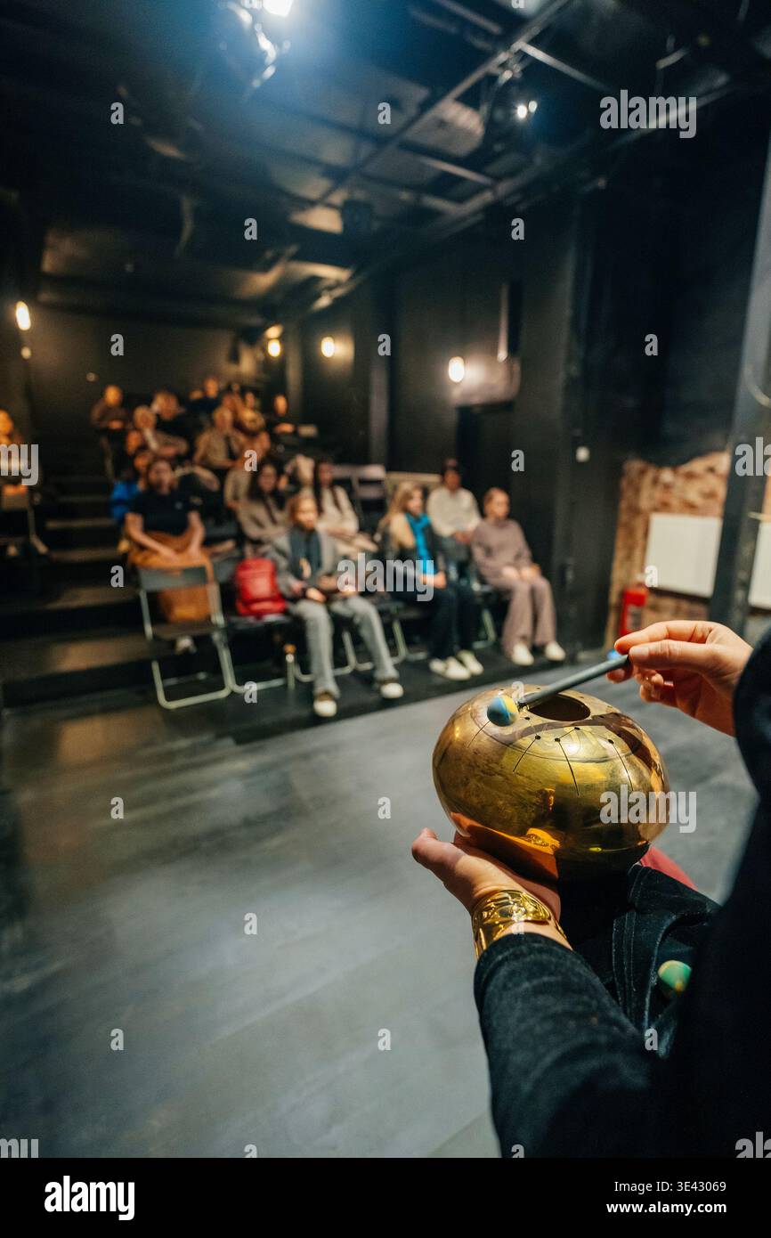Darsteller Hält Handpan Im Blackbox Theater, Dimmerlicht Und Mehrstufige Sitzplätze Mit Aufmerksamkeit. Stockfoto