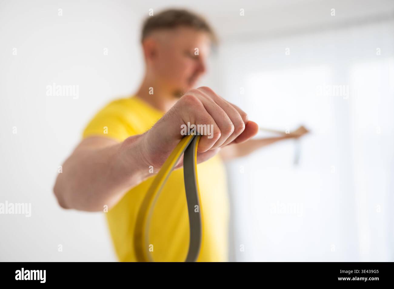 Sportliche Mannübungen zu Hause mit Einem Gummiband für starke Arme Stockfoto