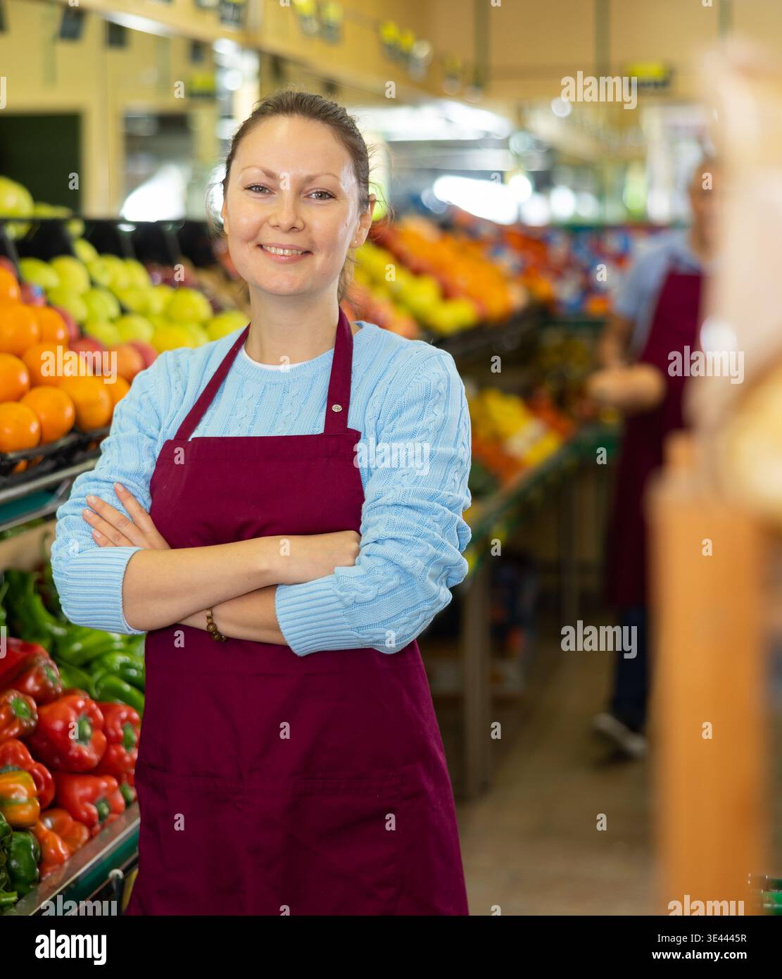 Eine Verkäuferin mittleren Alters, die vor der Theke im Lebensmittelgeschäft steht Stockfoto