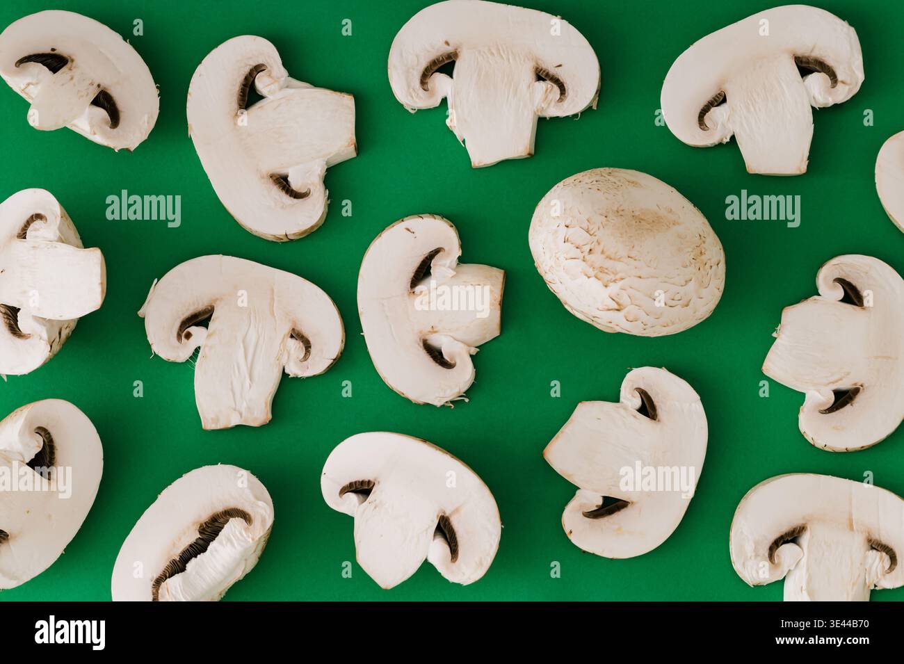 Champignon-Pilzmuster auf grünem Hintergrund. Lebensmittelkonzept. Frisch geschnittene Pilze flach legen. Stockfoto