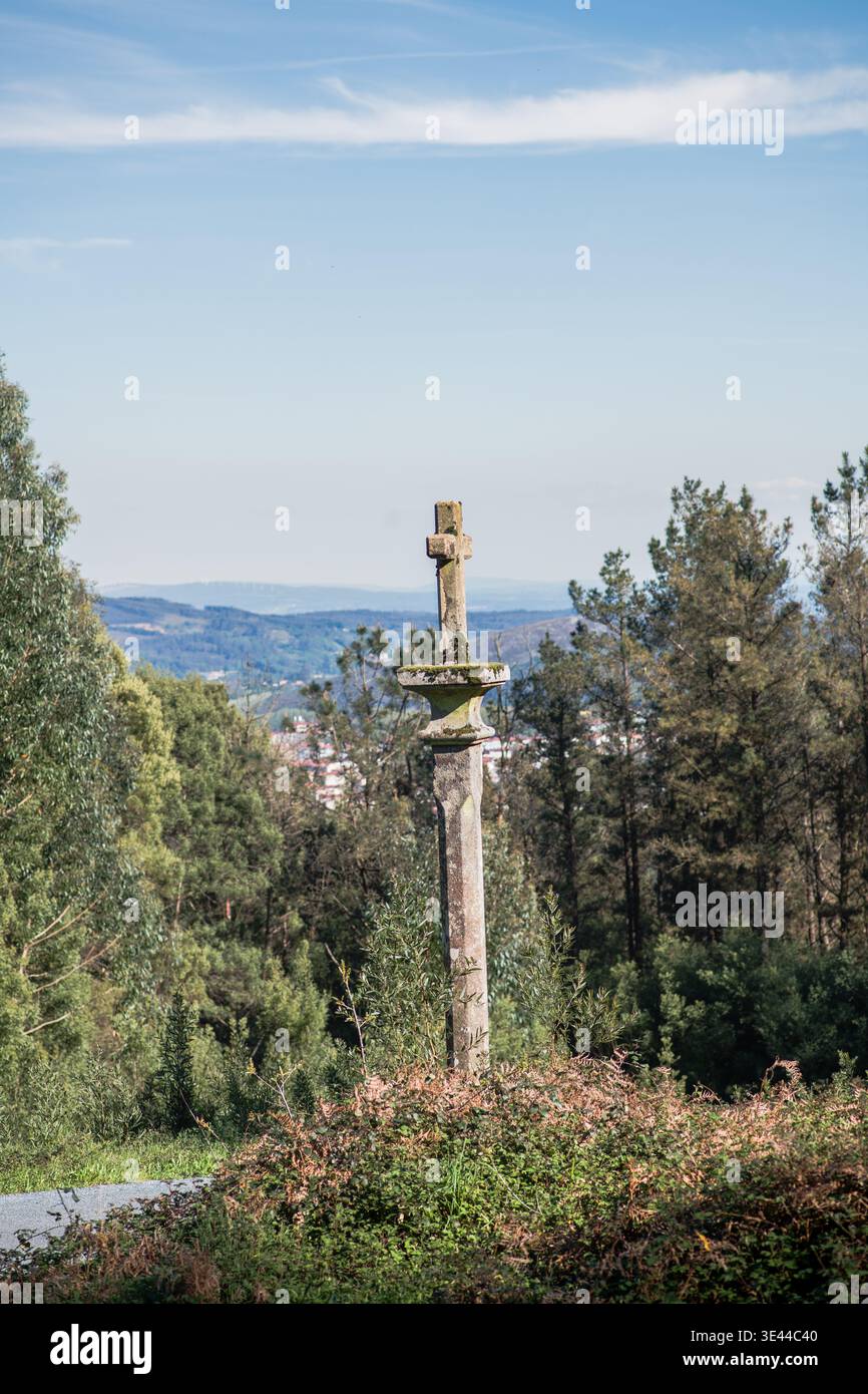 Steinkreuzdenkmal, Wächter auf einem Hügel, mit Blick auf ferne Hügel mit verstreuten Gebäuden und einem üppigen grünen Wald unter einem klaren blauen Himmel Stockfoto