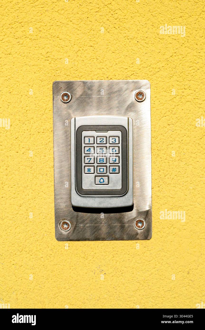 Modernes Türschloss mit digitaler Tastatur an gelber Stuckwand. Sicherheitszugangskontrollsystem für den Gebäudeeingang Stockfoto