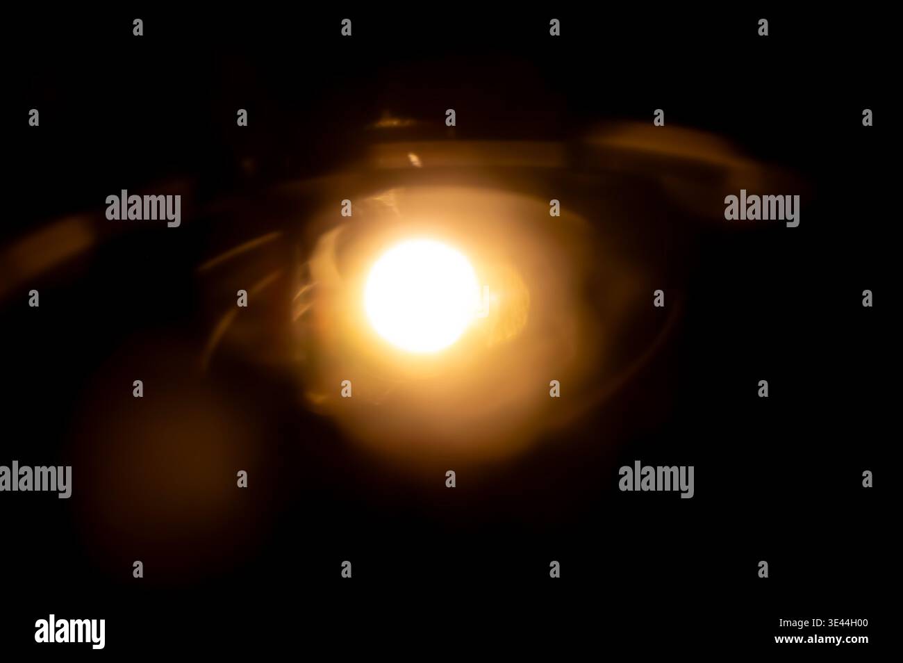Abstraktes, warmes orangefarbenes Objektiv mit Lichteffekt auf schwarzem Hintergrund, perfekt für kreative Blendungs- und Bokeh-Effekte auf Fotos Stockfoto