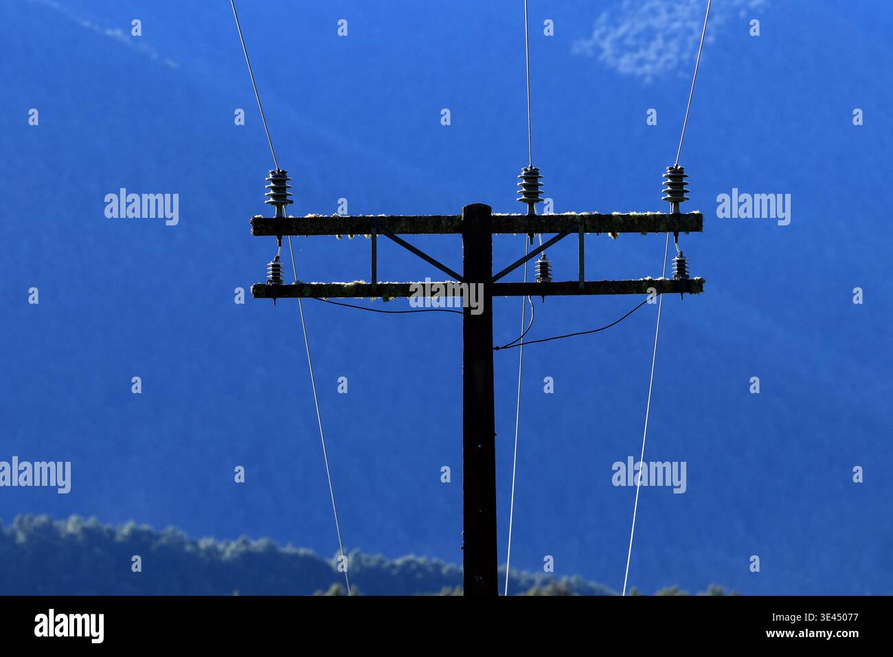 Strommasten und Leitungen gegen blauen Himmel Stockfoto