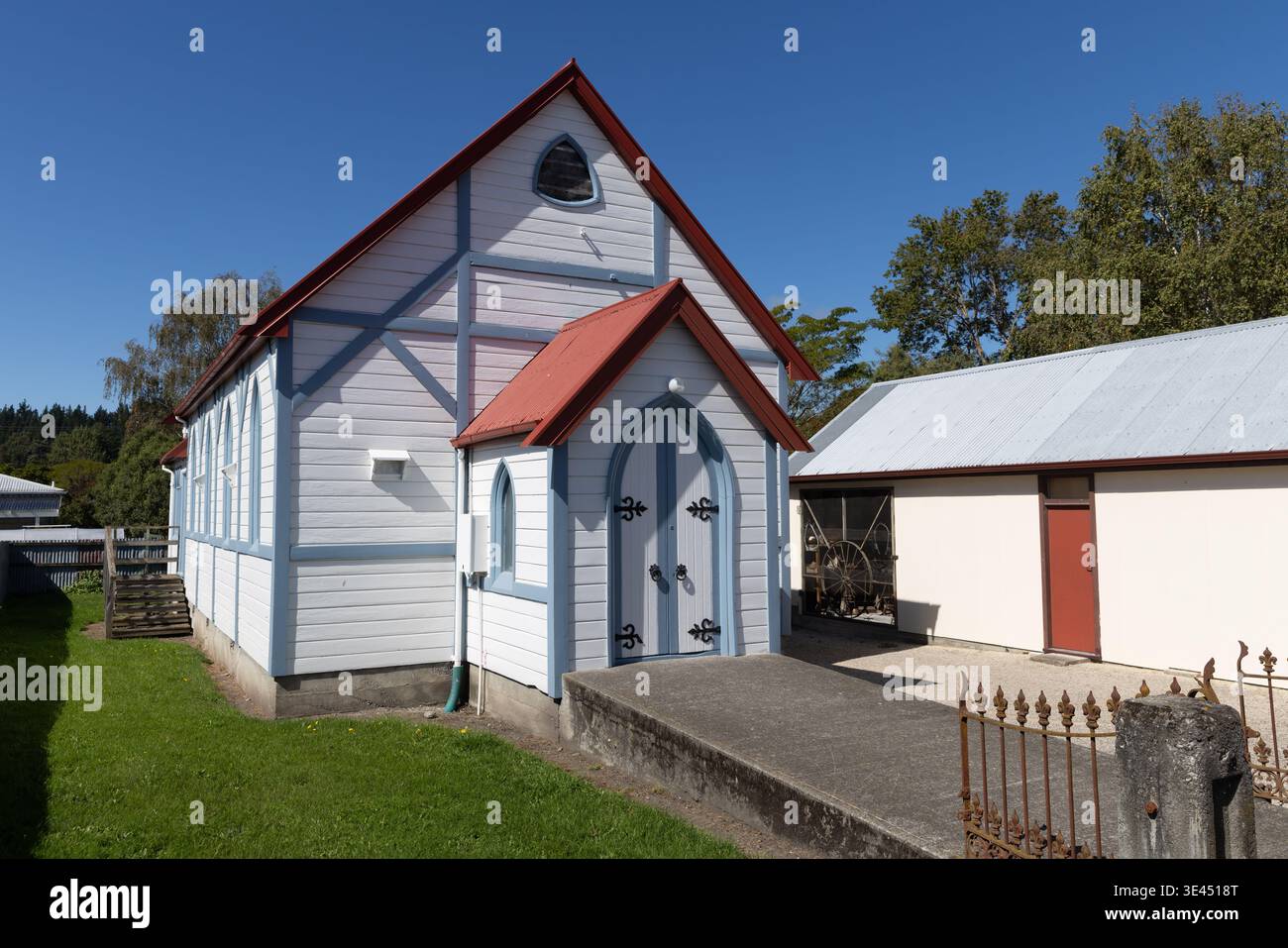 Kleine Holzkirche mit Giebeldach und bogenförmiger Tür neben dem Nebengebäude in ländlicher Umgebung, Südinsel, Neuseeland Stockfoto