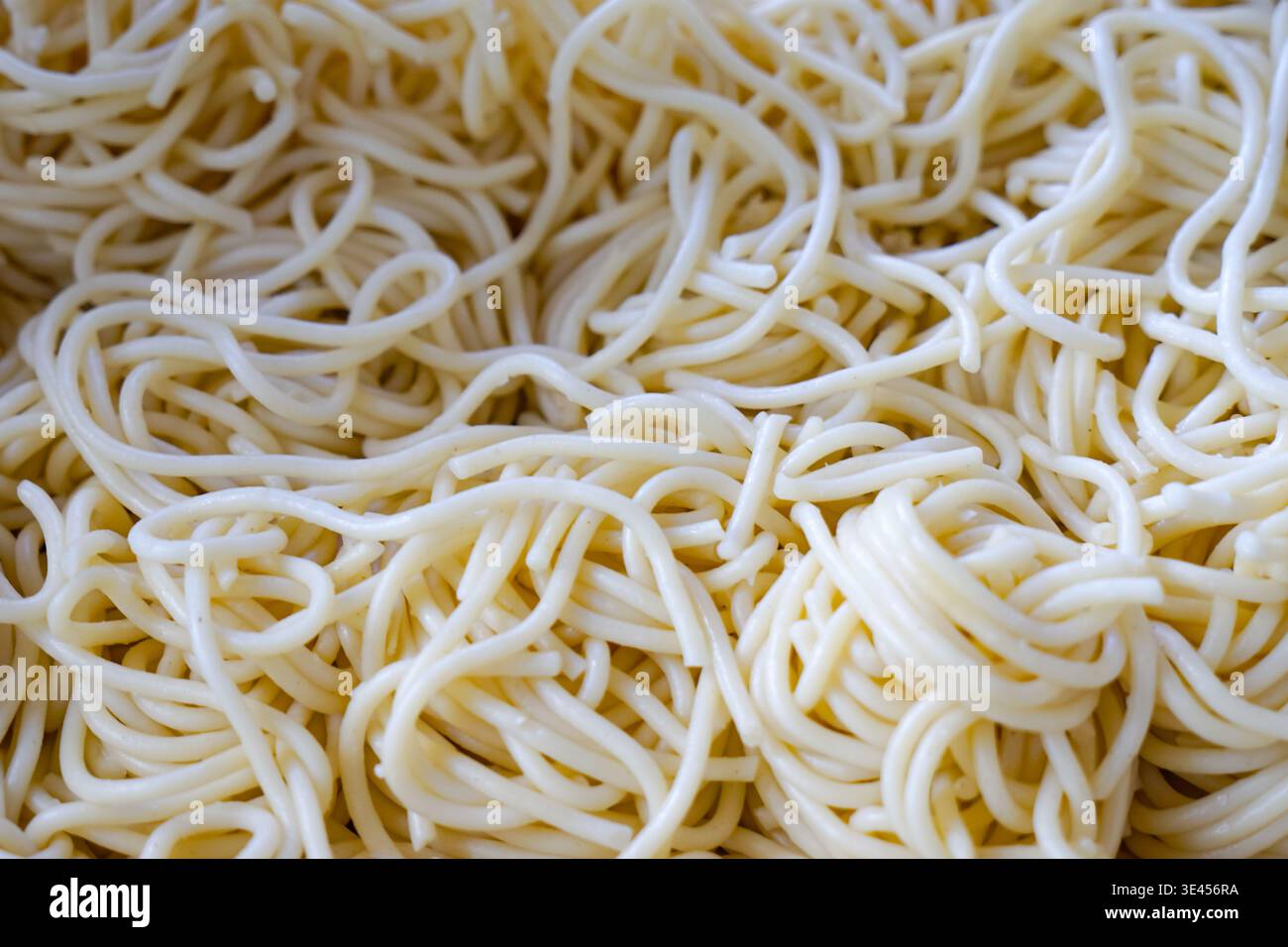 Nahaufnahme von einfachen Spaghettinudeln, hellgelb und glatt, die Nudeltextur vor dem Hinzufügen von Sauce oder Toppings hervorheben. Stockfoto