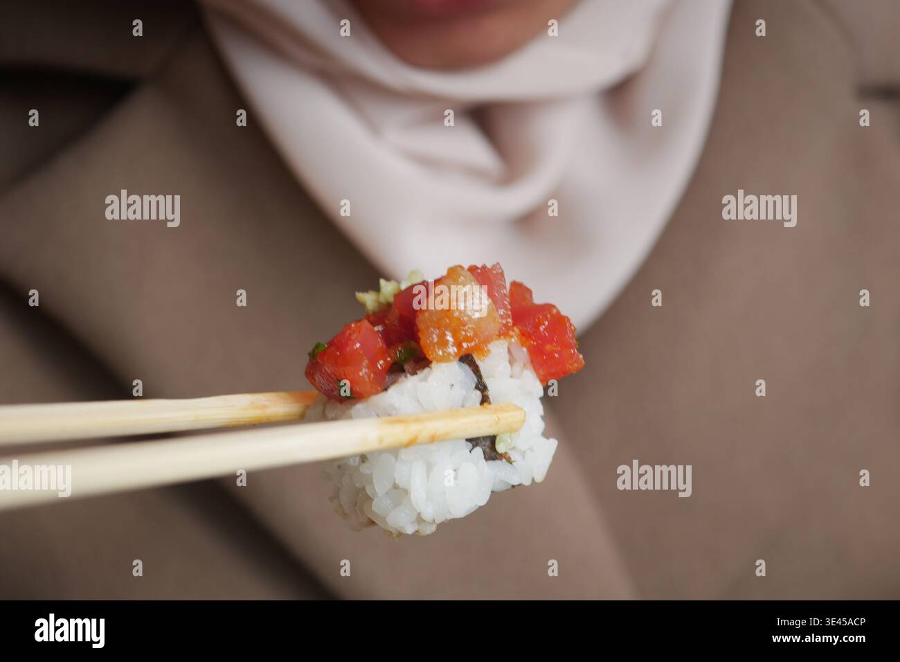 Frau isst Sushi mit Essstäbchen in einer zwanglosen Umgebung Stockfoto