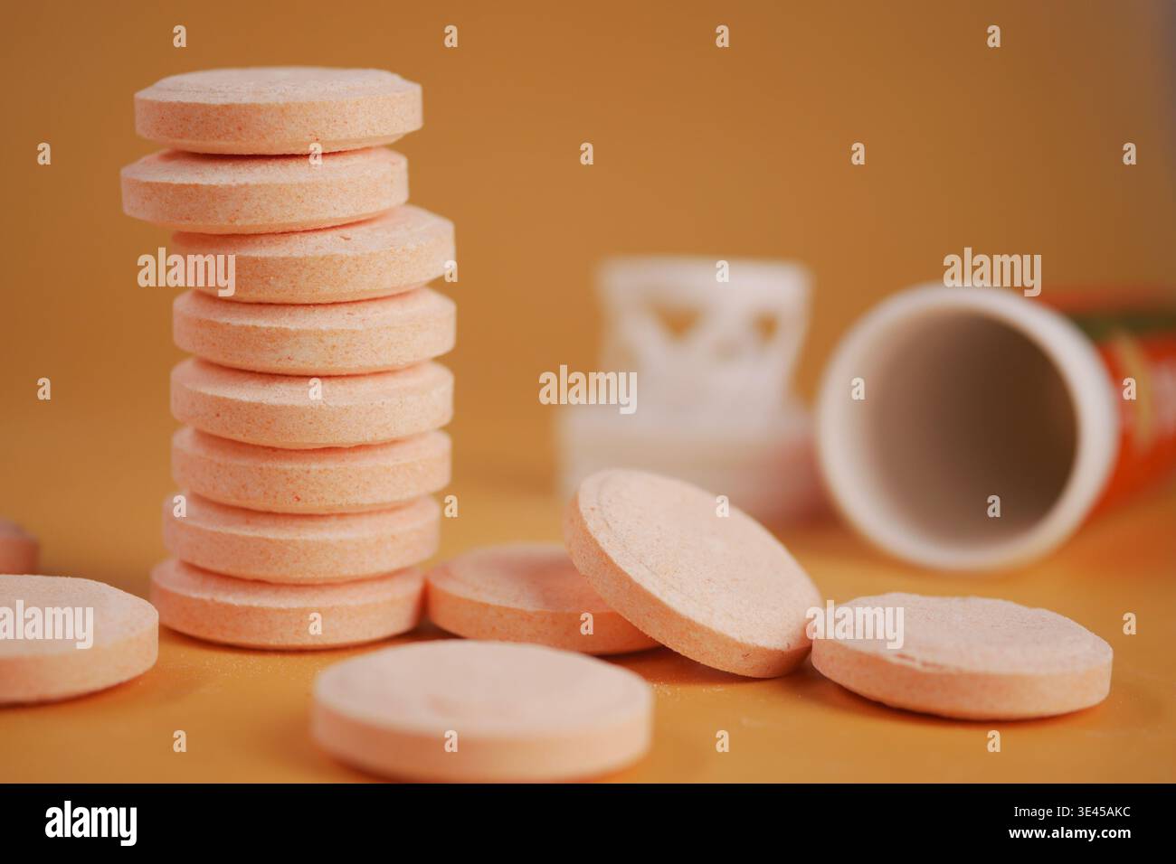 Ein Stapel runder Vitamin-C-Tabletten steht auf einer gelben Oberfläche. Stockfoto