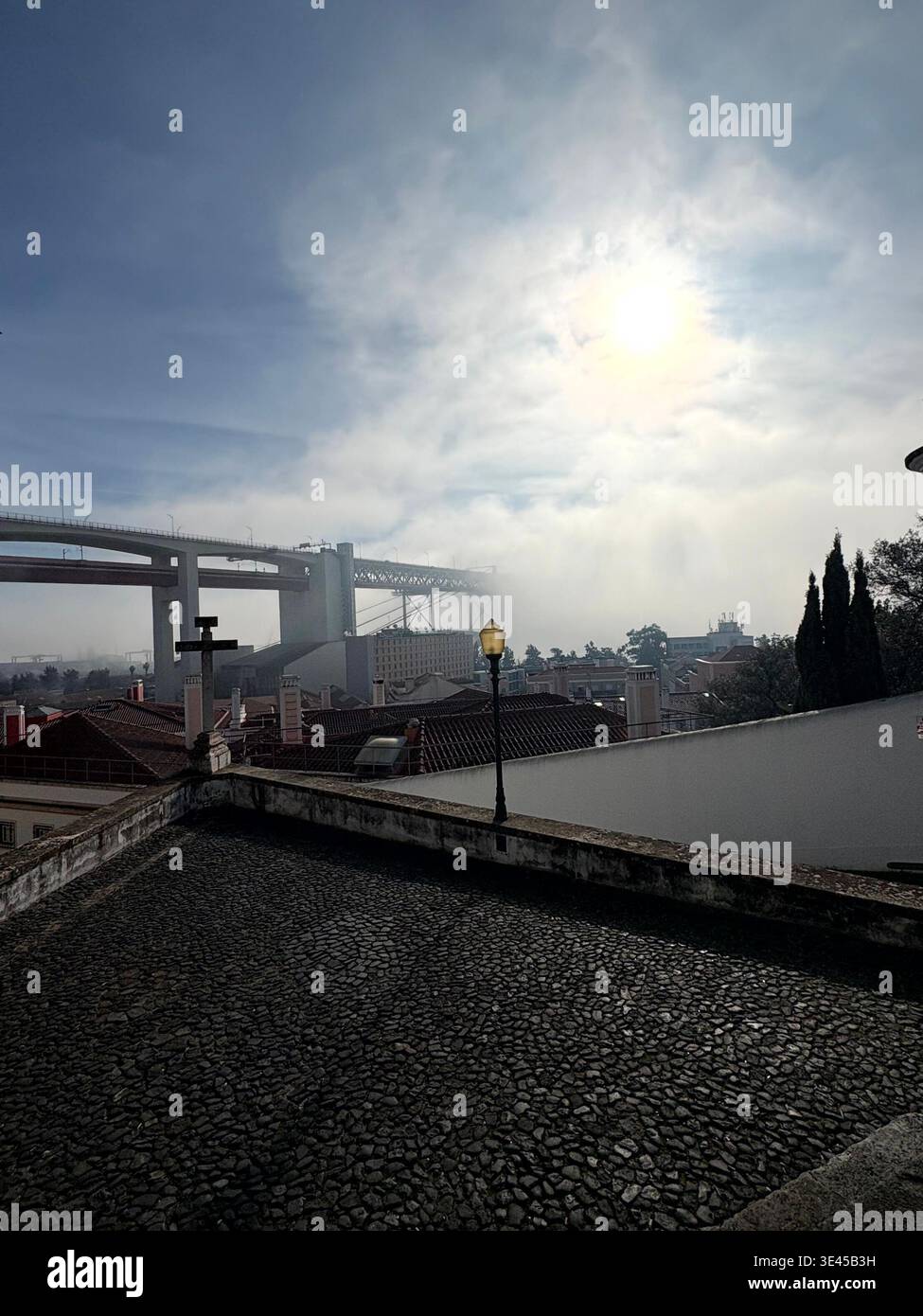 Aussichtspunkt mit Straßenlaterne und erhöhter Brücke in Foggy Coimbra - Smartphone-aufgenommenes Stockfoto