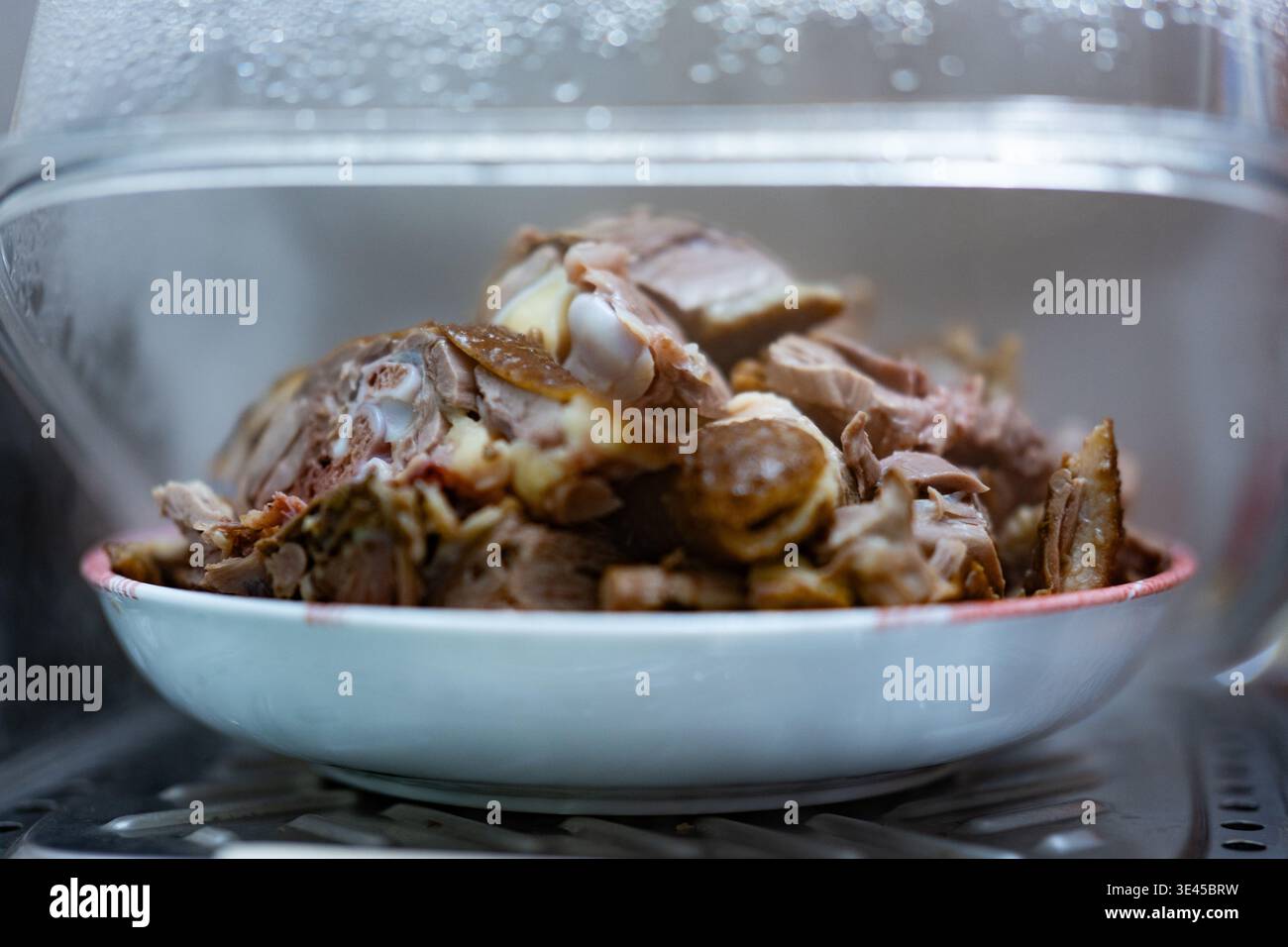 Gedämpfte Lammkäfer in weißer Schüssel unter Glasdeckel, chinesische Küche, Peking Stockfoto