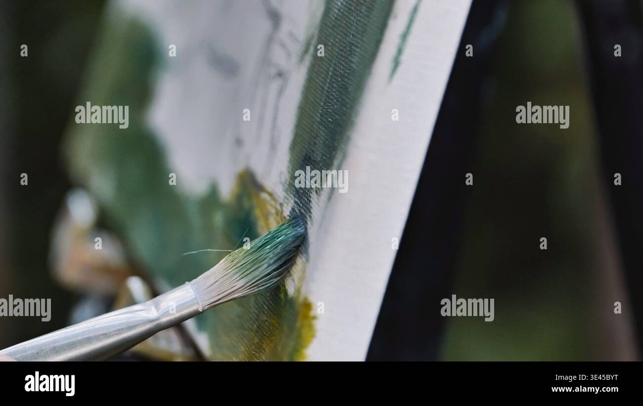 Künstler malte Landschaft im Freien auf Leinwand mit einem Pinsel, der grüne Farbe in Moskau aufträgt Stockfoto