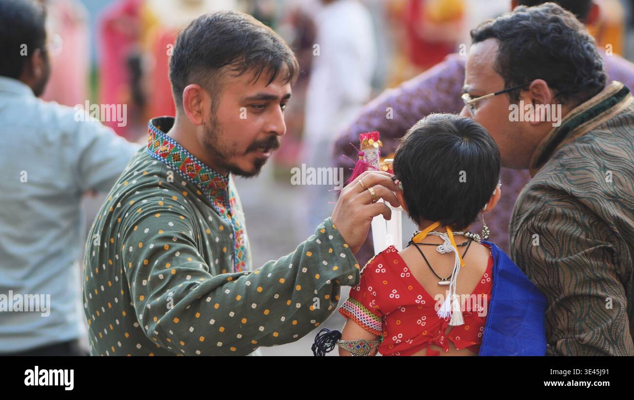 Delhi, Indien - 19. September 2025: Mann kleidet Kind in traditioneller indischer Kleidung für das Ganesh Chaturthi Festival Stockfoto