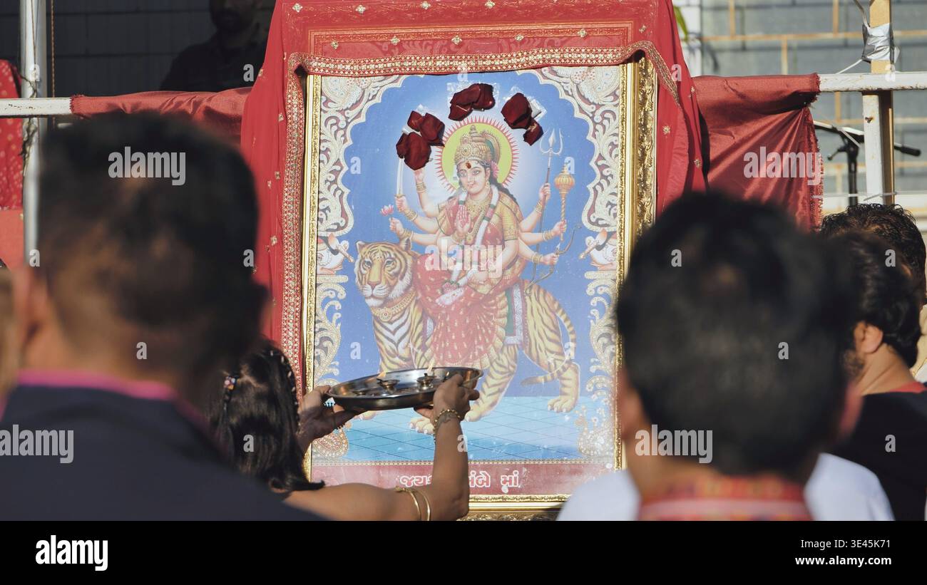 Hinduistische Anhänger treffen sich zu einer Puja im Freien und verehren ein gerahmtes Bild von Göttin Durga Stockfoto