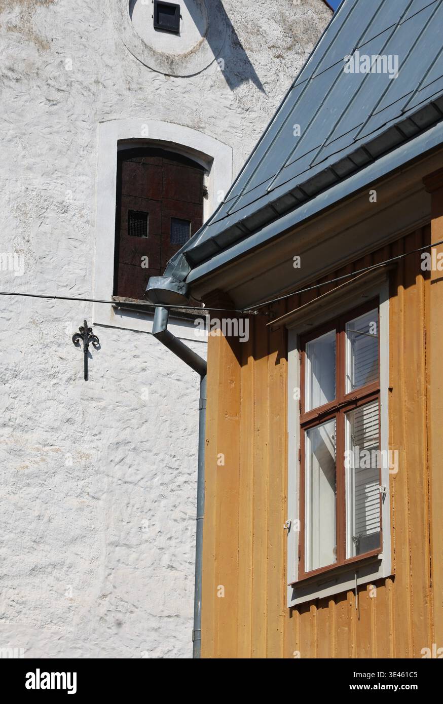 Detail der traditionellen skandinavischen Architektur mit einer hölzernen Hausfassade mit einem Fenster neben einem weißen Putzgebäude. Das Bild hebt den Text hervor Stockfoto