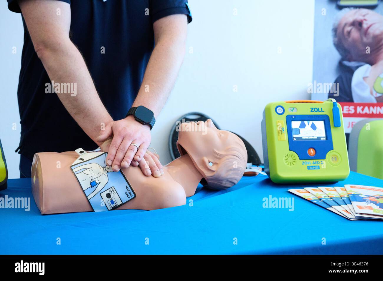 Berlin, Deutschland. März 2026. Ein Mitarbeiter des Zoll Medical AED demonstriert den Schülern der Cosmopolitan School die Reanimation mit einer Reanimationspuppe und demonstriert Thoraxkompressionen, während ein automatisierter externer Defibrillator (AED) auf einem Tisch daneben steht. Das Projekt „Staying Alive“, initiiert von H. Bauckhage, einem Abitur, zielt darauf ab, junge Menschen in Notsituationen richtig zu handeln. Ziel ist es, die Öffentlichkeit für das Thema Wiederbelebung zu sensibilisieren. Annette Riedl/dpa/Alamy Live News Stockfoto