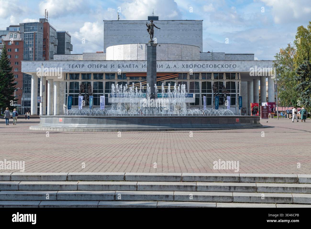 KRASNOJARSK, RUSSLAND - 12. SEPTEMBER 2025: Brunnen und Apollonsäule auf dem Hintergrund des Opern- und Balletttheaters an einem sonnigen Septembertag Stockfoto