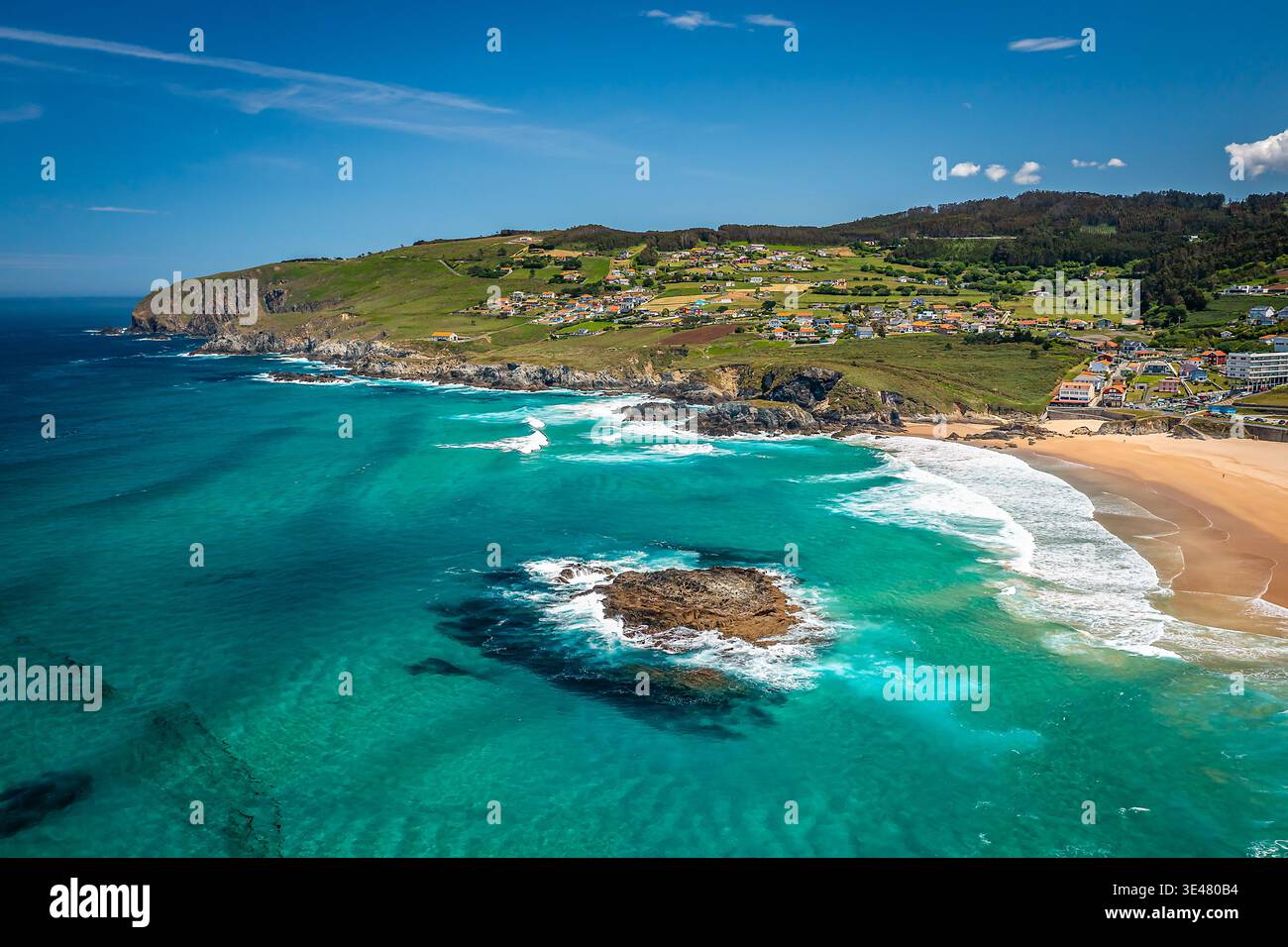 Luftpanorama der Küste mit türkisfarbenen Meereswellen, die auf einen breiten goldenen Sandstrand in Valdovino, Spanien brechen Stockfoto
