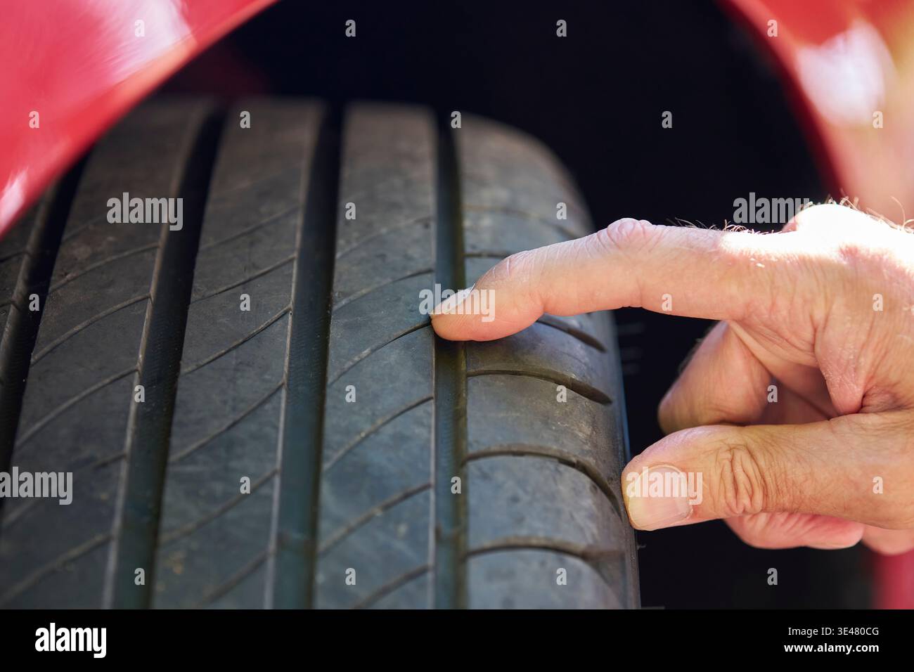 Nahaufnahme eines Mannes, der die Reifenprofiltiefe am Fahrzeug überprüft Stockfoto
