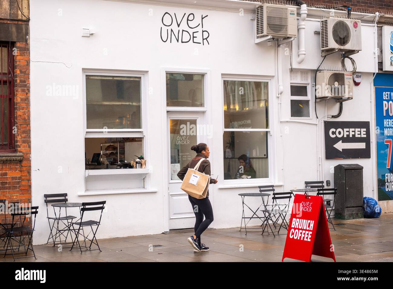 LONDON - 2. FEBRUAR 2026: Über dem Außenbereich des Cafés mit Kunden und A-Rahmen-Schild an der Earl's Court Street Stockfoto