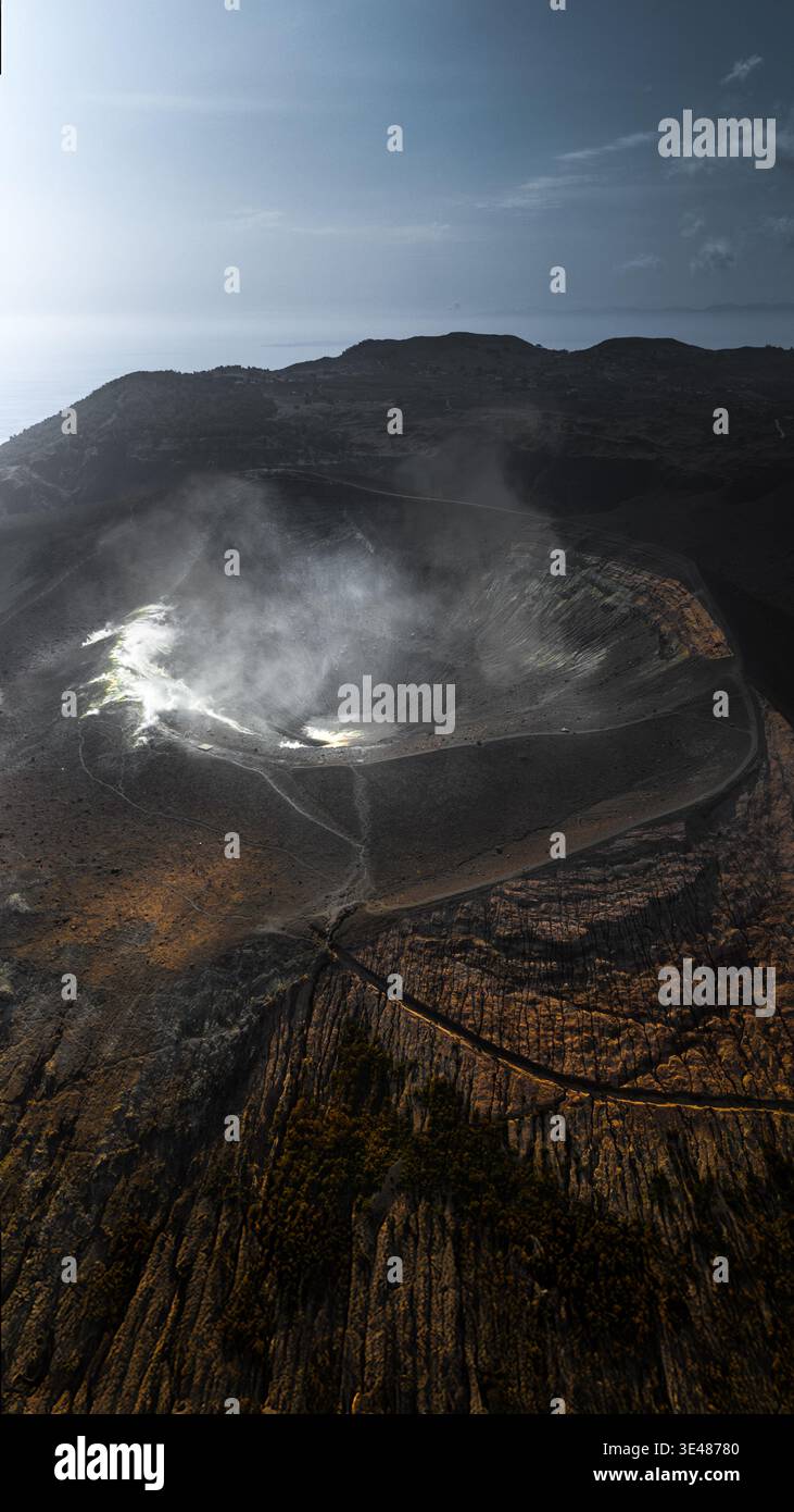 Aus der Vogelperspektive des vulkanischen Kraters der Äolischen Inseln mit aufsteigendem Dampf und schroffem, dunklem Gelände in Sizilien, Italien. Stockfoto