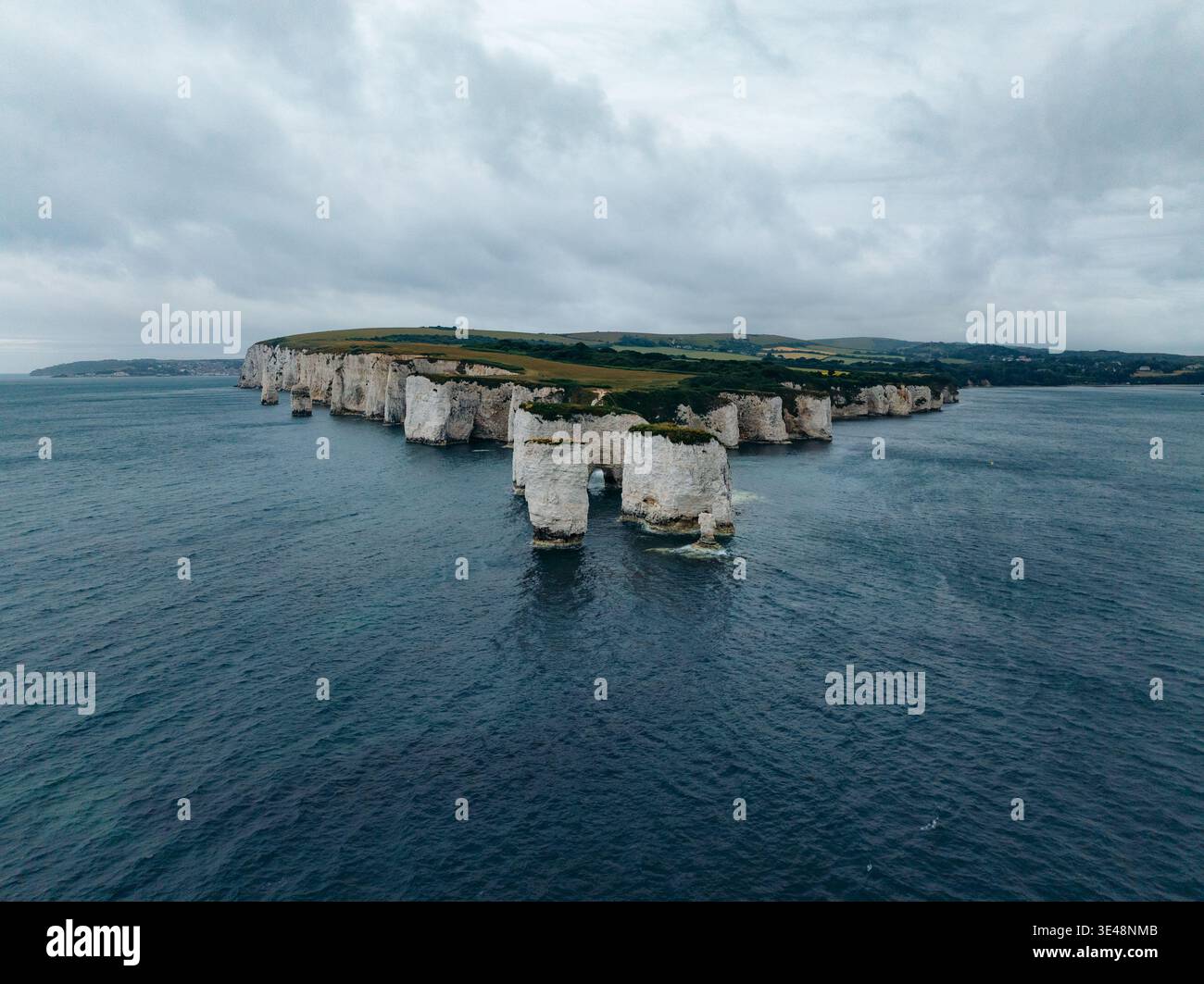 Aus der Vogelperspektive sehen Sie die Kalkstapel trotzig vor dem unerbittlichen Meer, deren weiße Klippen im Kontrast zu dem tiefblauen Wasser rund um Old Harry R stehen Stockfoto